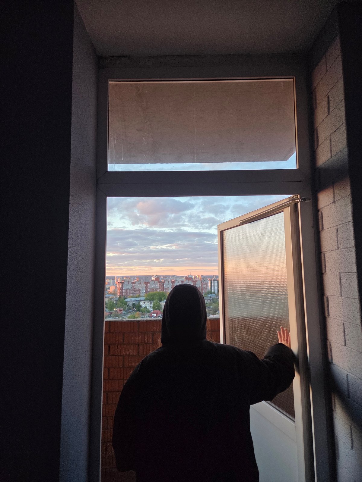 Person watches sunset from Perm rooftop while using smartphone