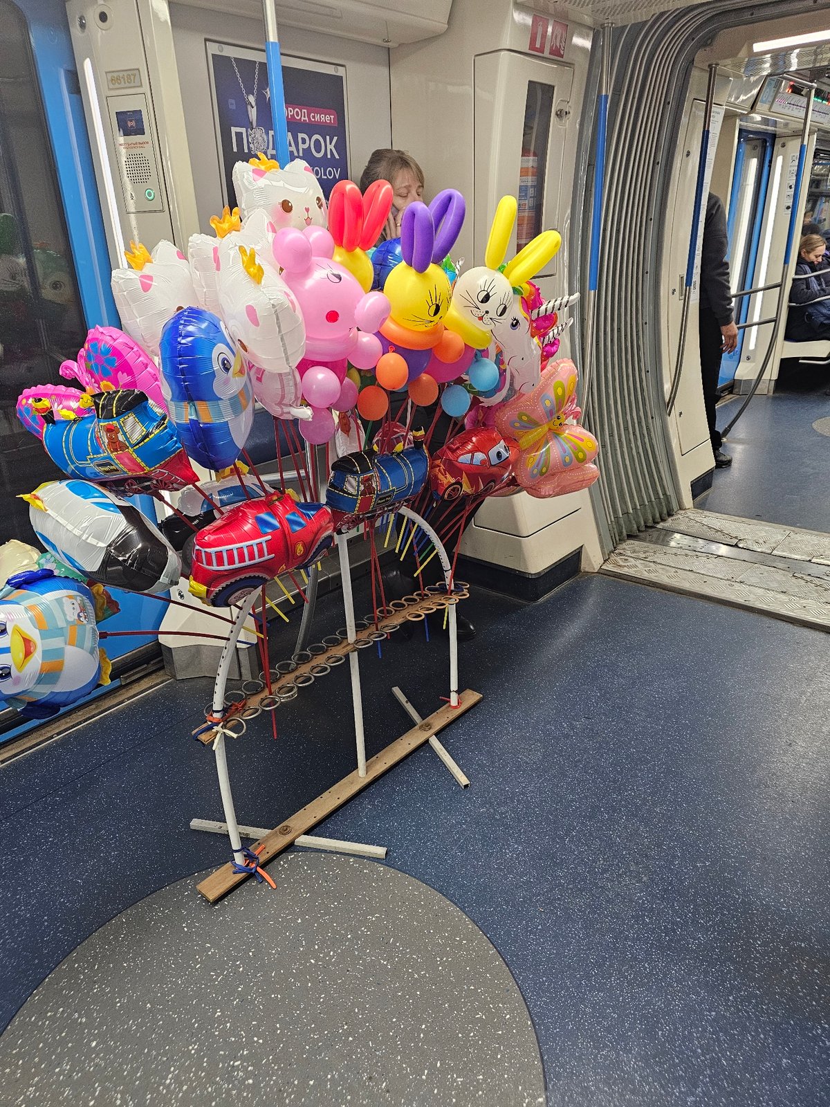 Balloon vendor sells animal-shaped balloons on Moscow Metro train
