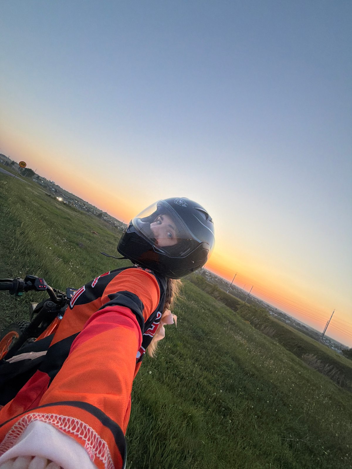 Woman cycles through Russian field at sunset