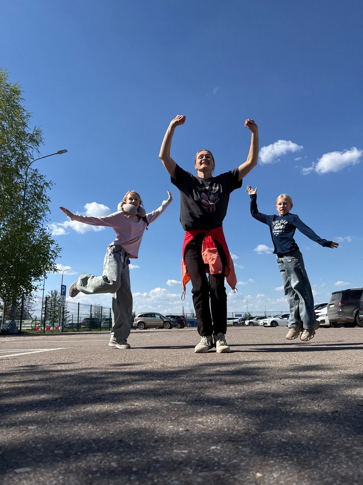 Three people pose and dance at Ufa Airport parking lot