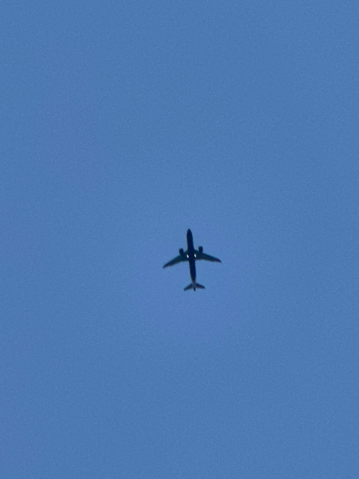 Planes and a crescent moon cross a clear London sky
