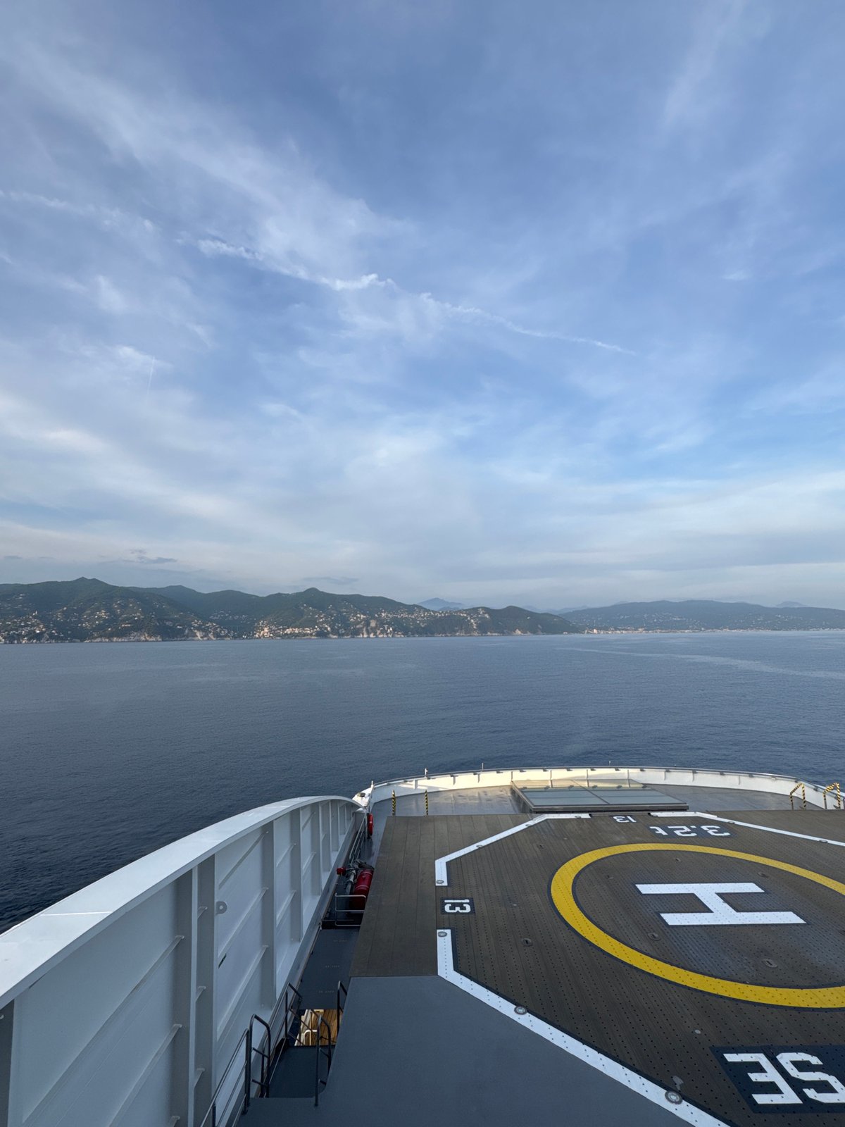Ship passenger observes coastal mountains under cloudy skies