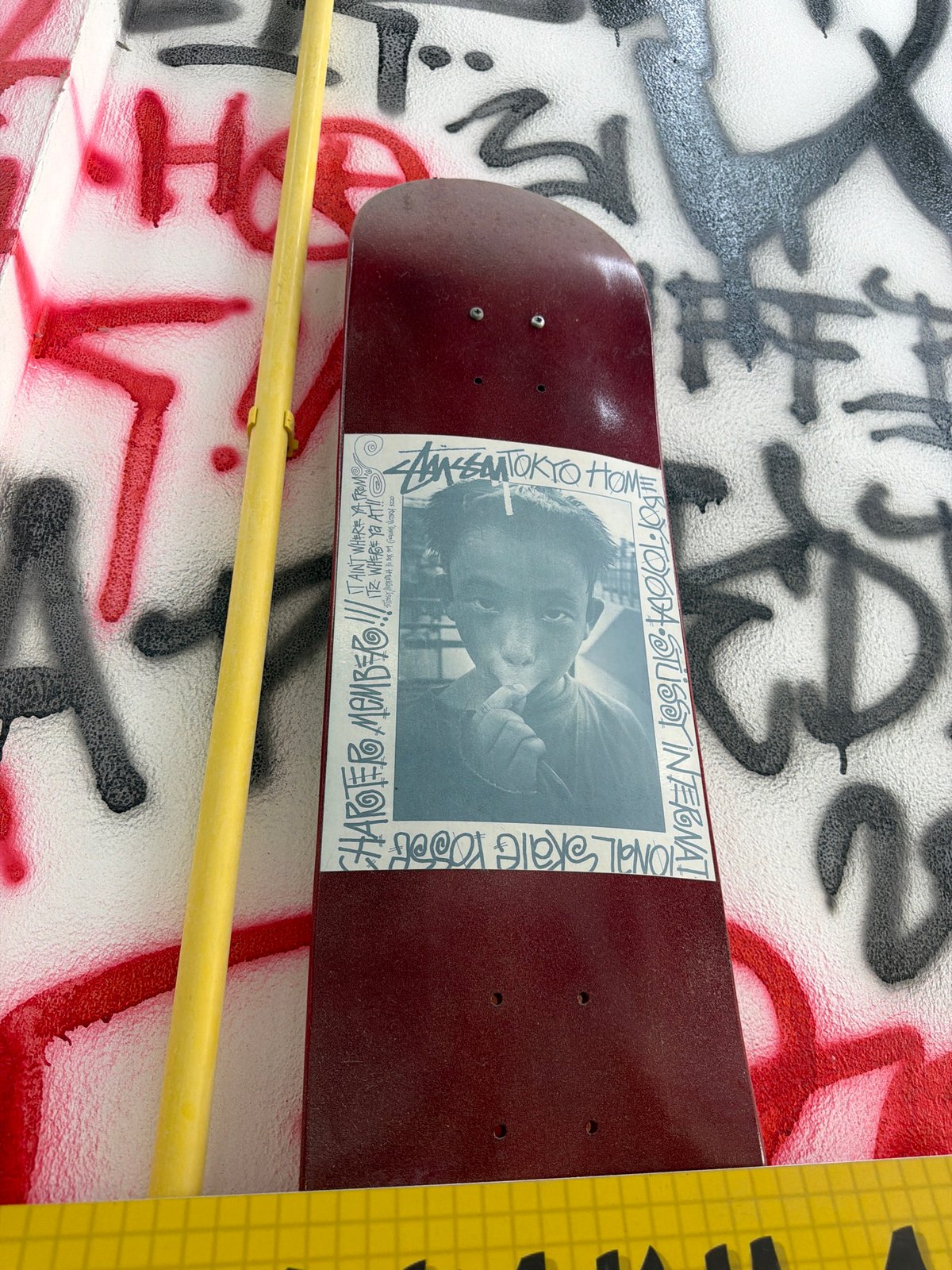 Skateboard with sticker spotted on graffitied wall in Chalong