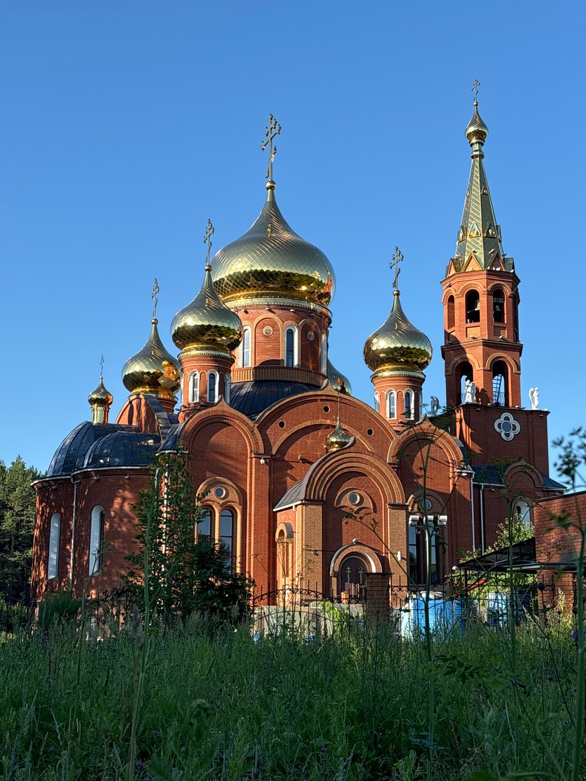 Red brick Orthodox church with golden domes in Chaikovsky