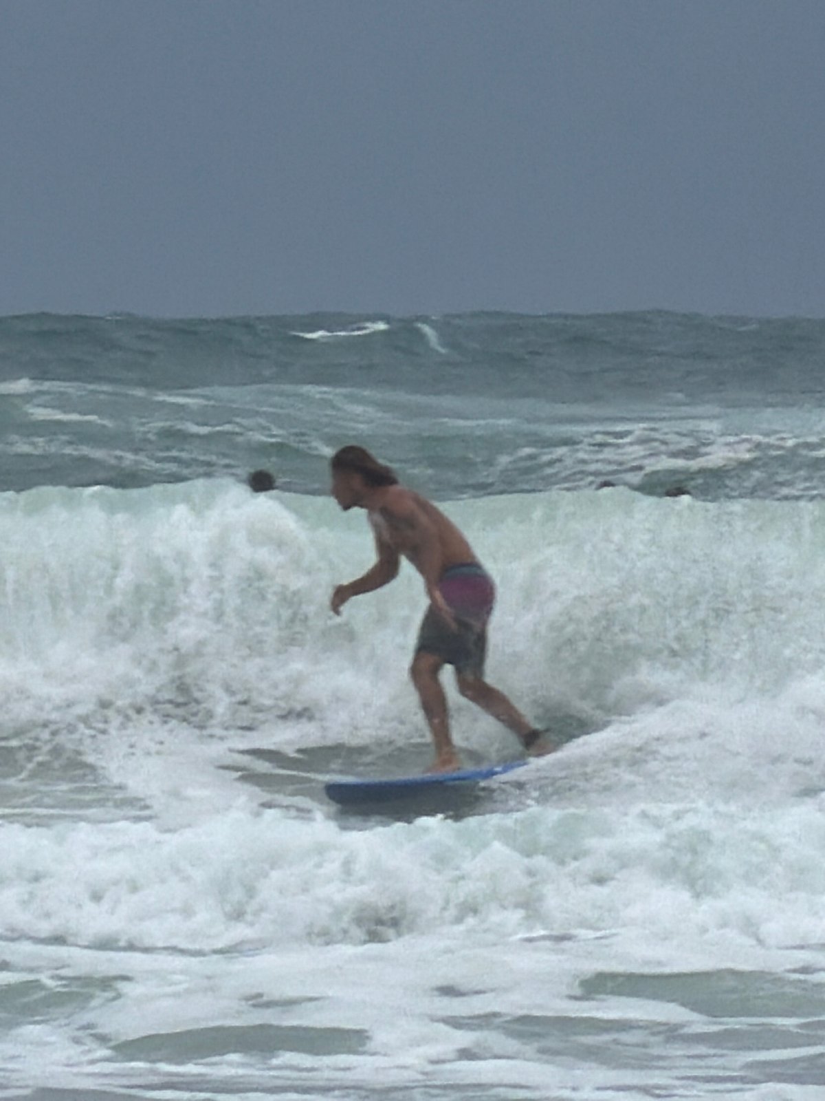 Surfer rides waves near Tel Aviv breakwater amid choppy conditions