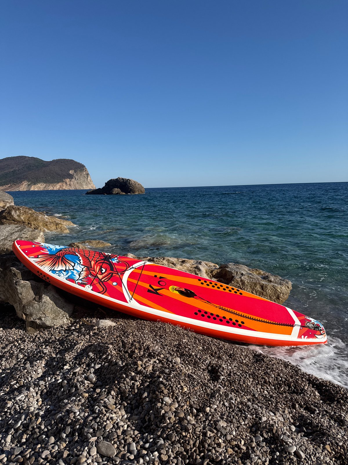 Koi-design paddleboard parked on a rocky Montenegrin beach
