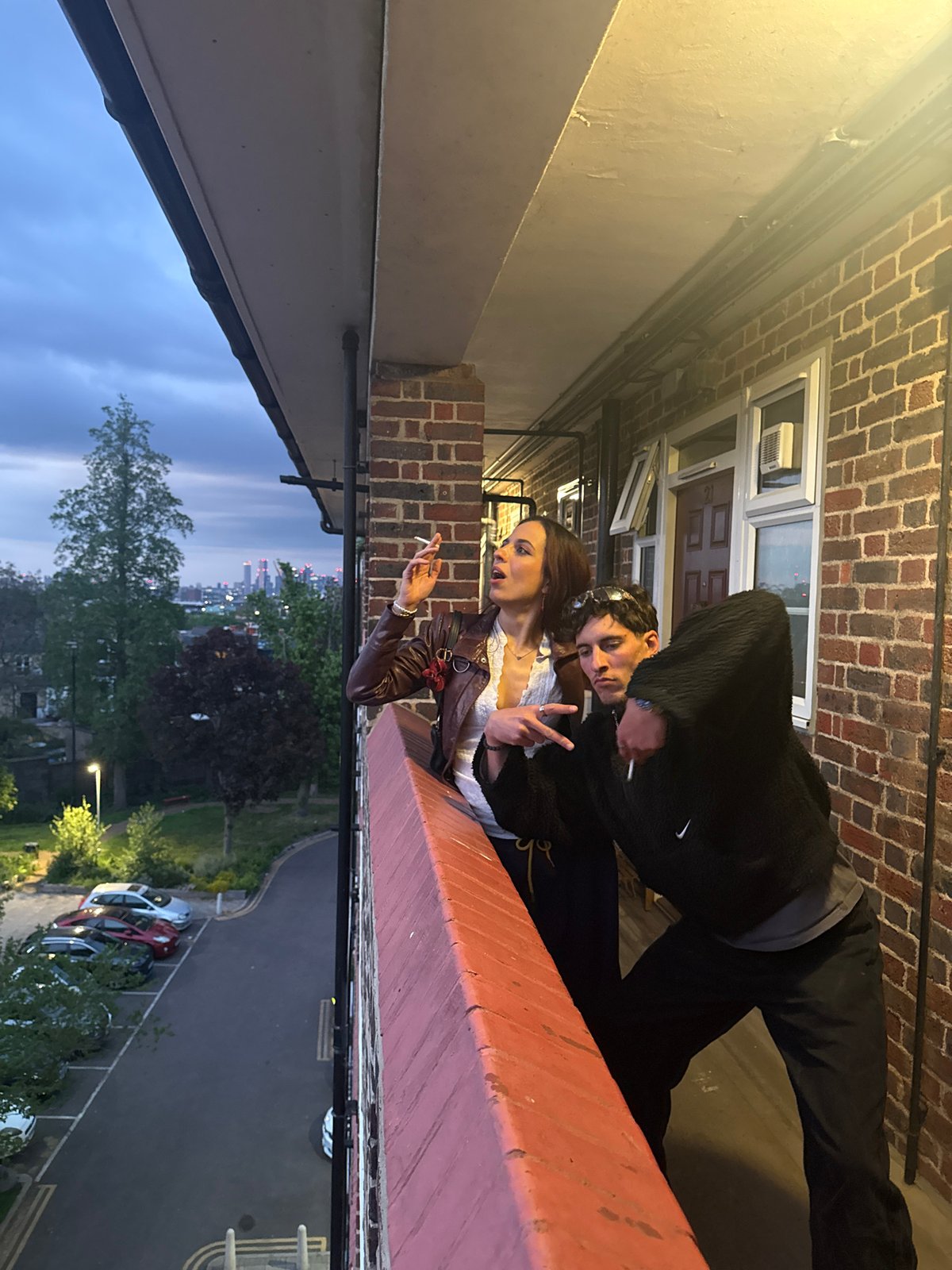 Two people share quiet moment on London balcony at dusk