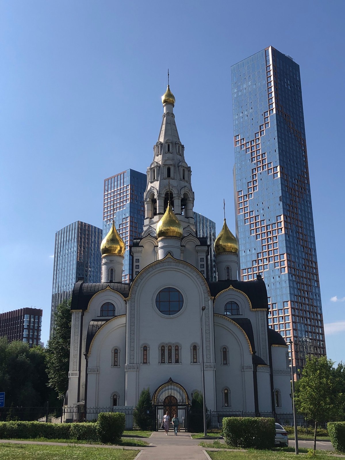 Orthodox church with golden domes against a modern glass skyline