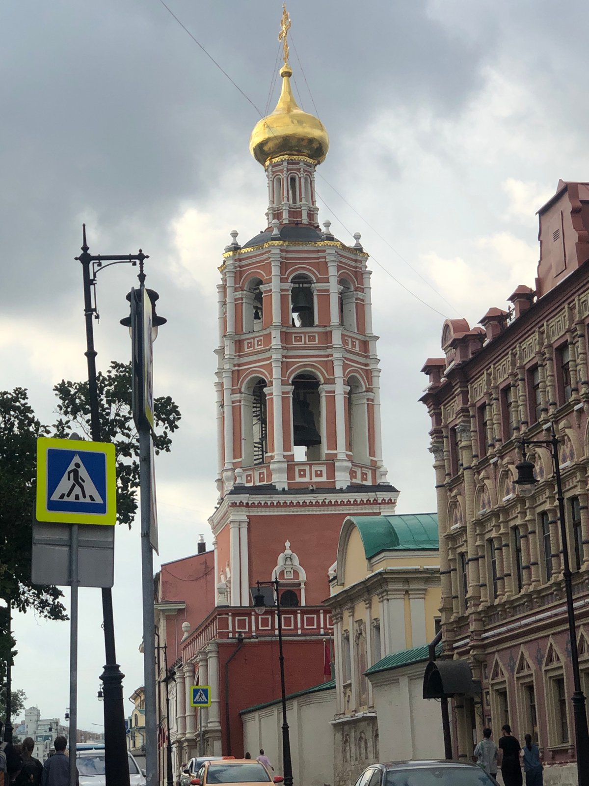 Bell tower and cafe life on a cloudy Cyrillic-script city street