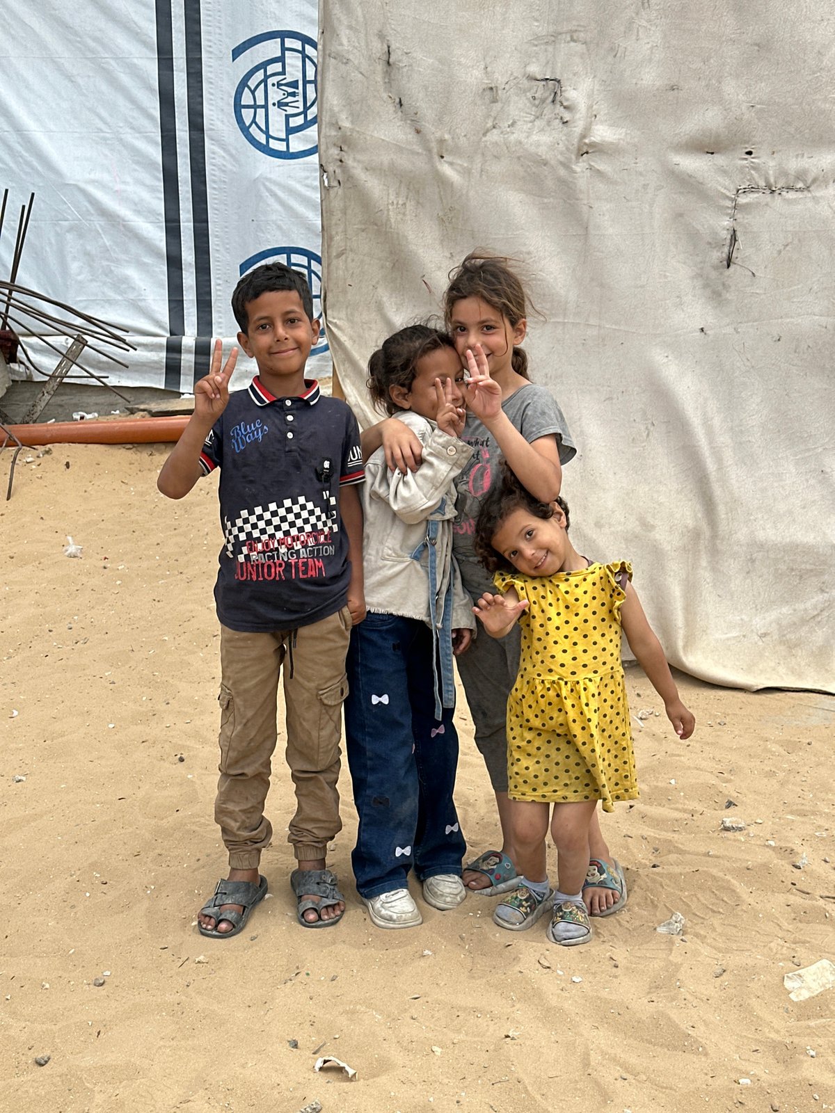 Four children lying together in sandy area in Gaza