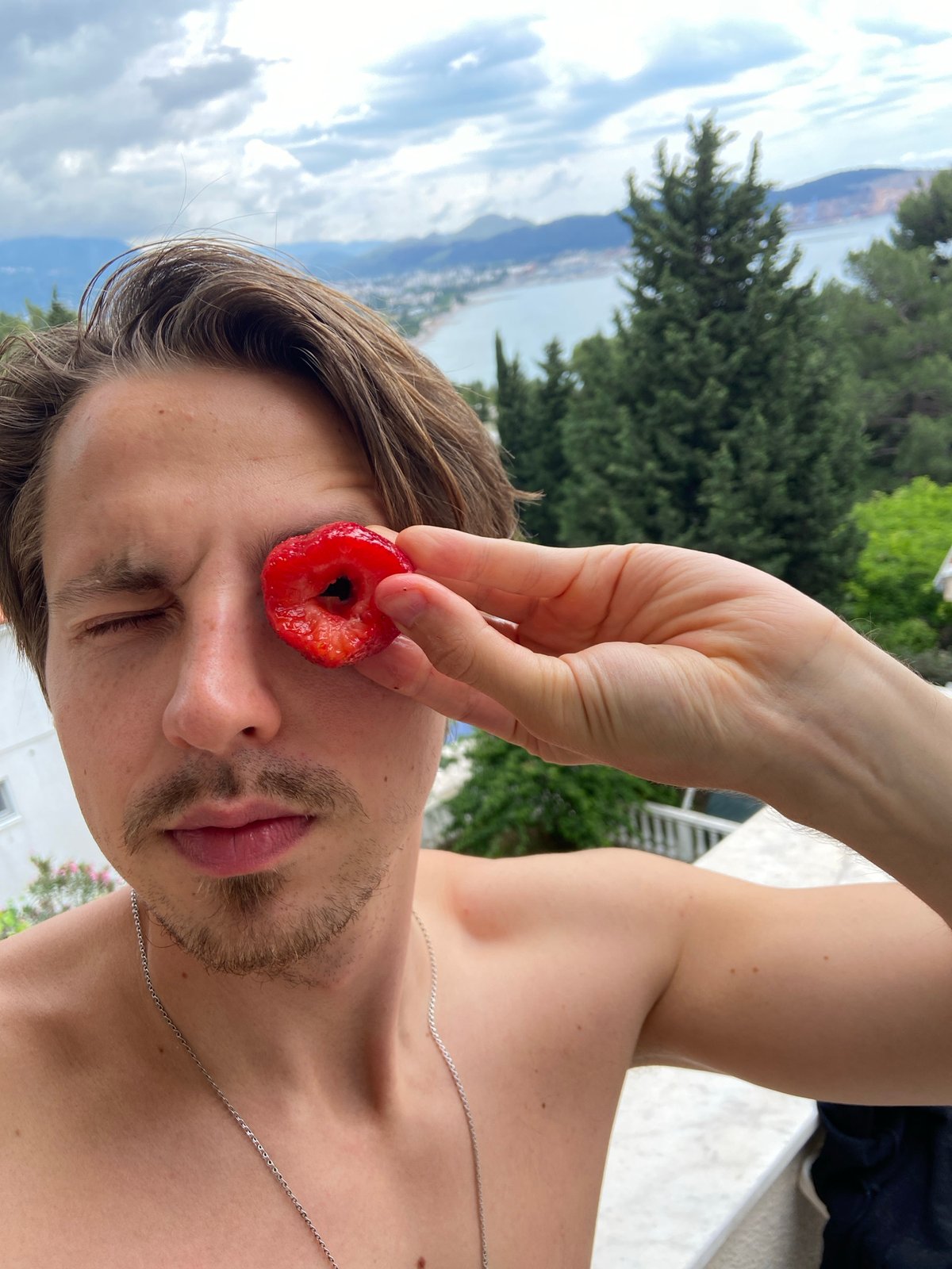 Man playfully eats strawberries in Montenegro coastal town