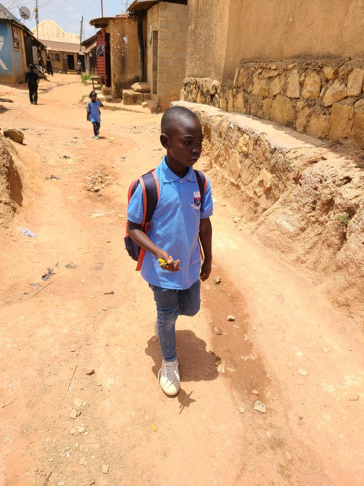 Pedestrians gather on dirt road in urban area