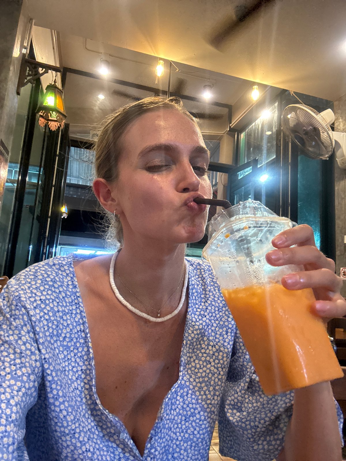 Woman enjoys orange drink in Patong cafe
