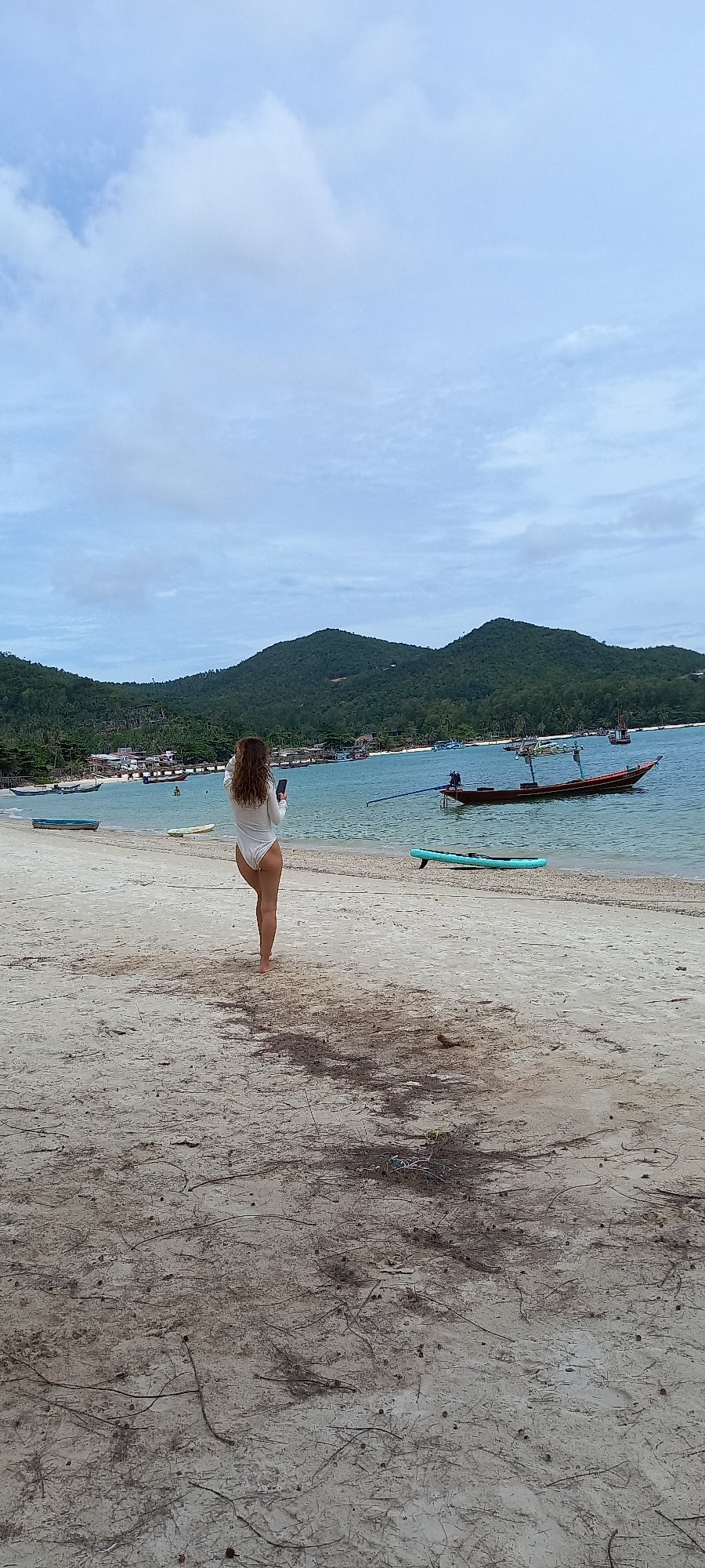 Woman with paddleboard spotted at Thai beach among boats
