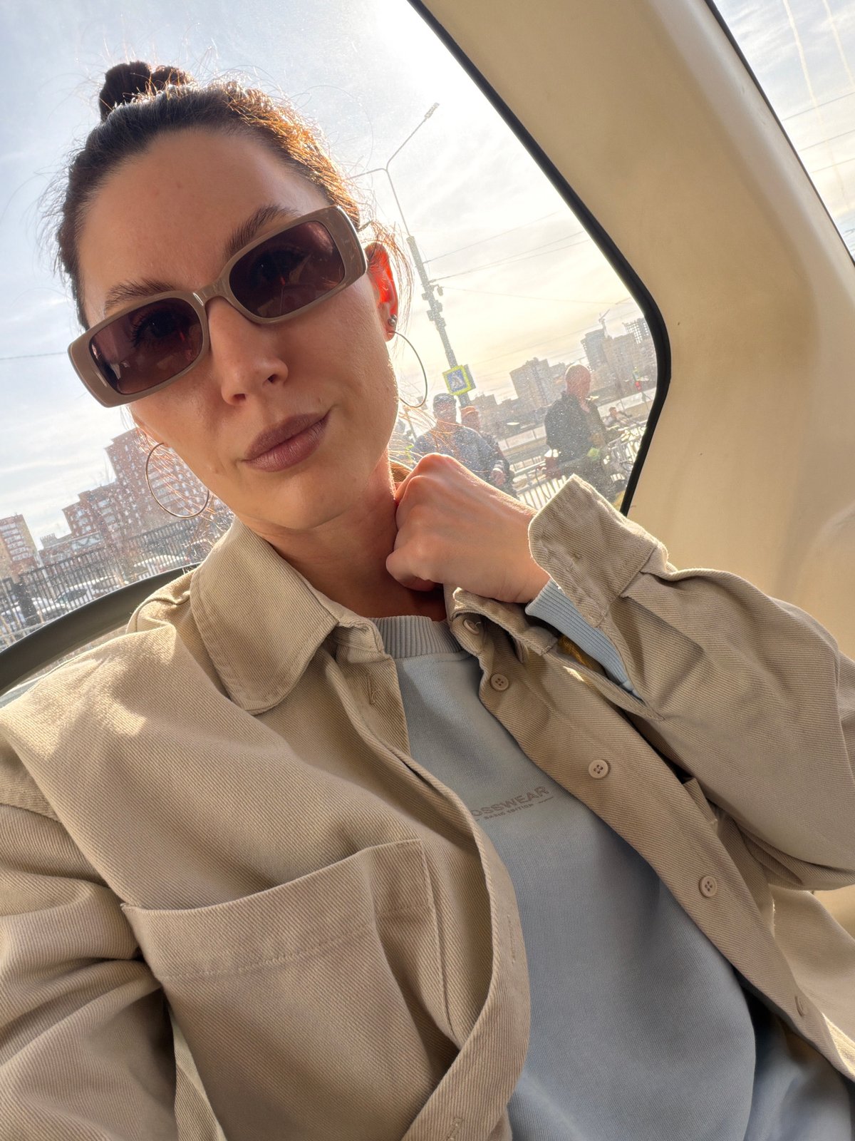 Woman takes selfie in vehicle with Perm cityscape backdrop