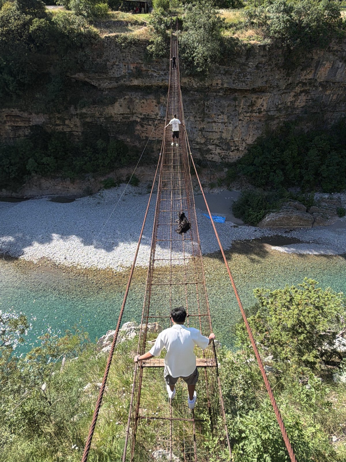 Tourists cross rustic suspension bridge over Montenegro river gorge