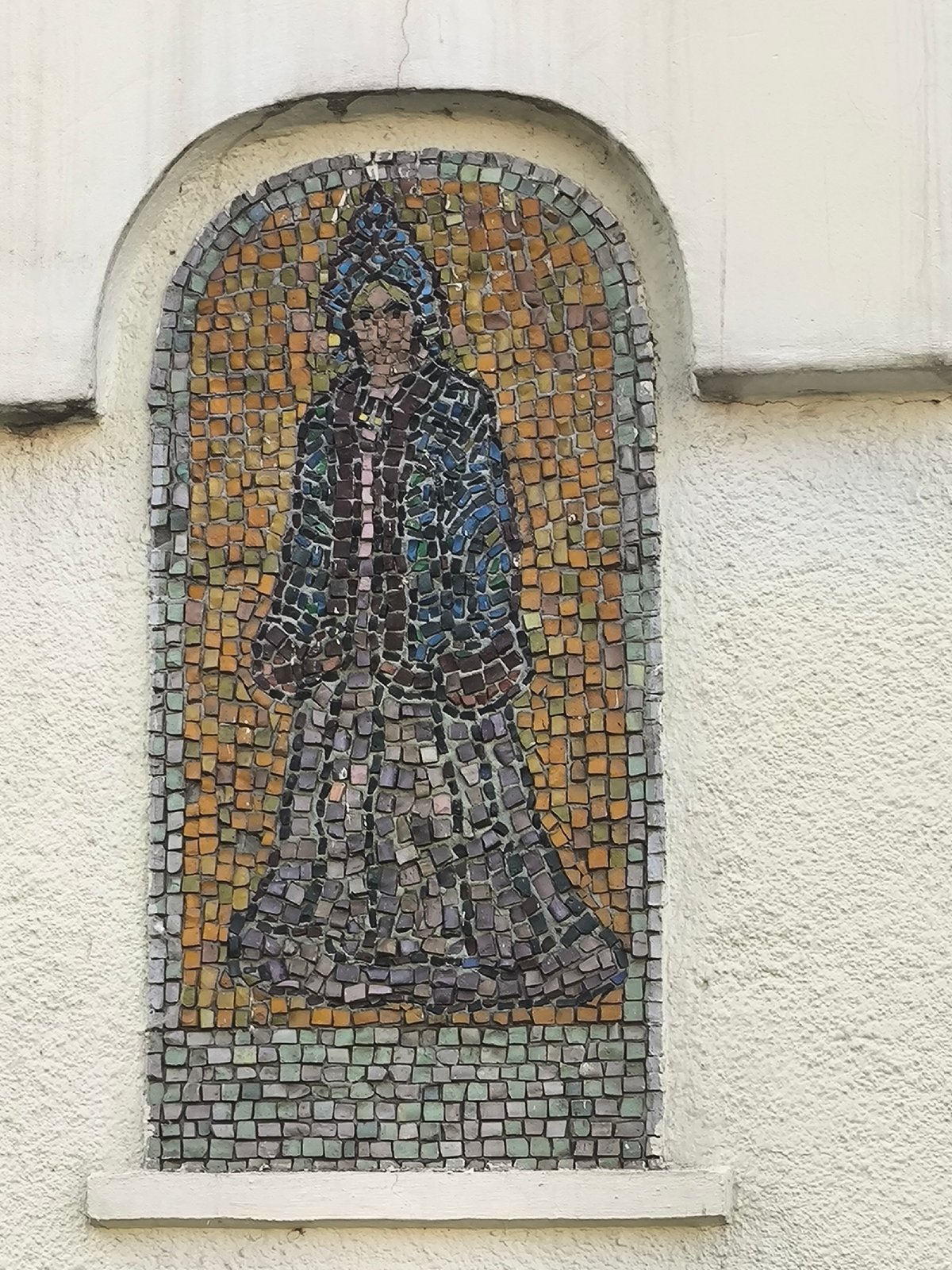 Ornate mosaic facade with robed figures and landscape murals