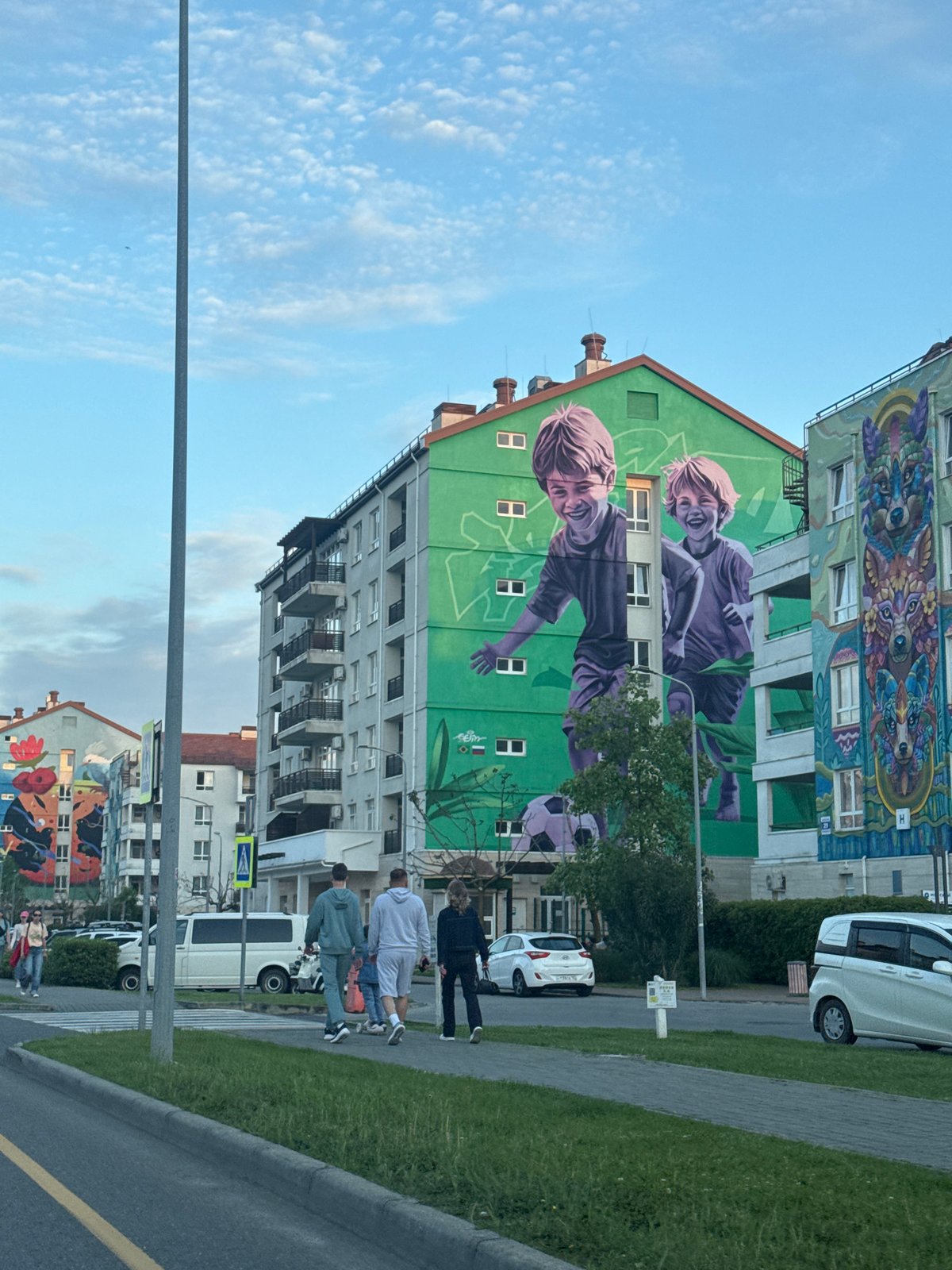 Pedestrians gather near mural-decorated building in Sirius, Russia