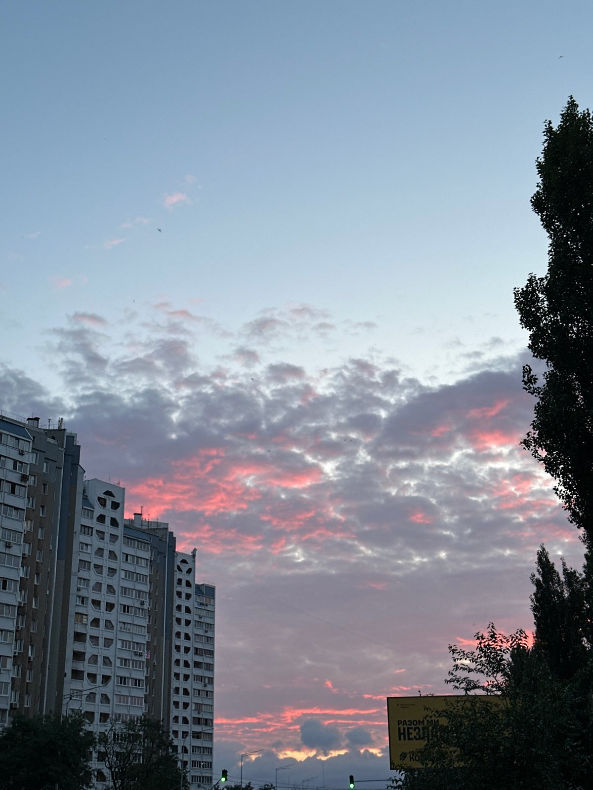 Kyiv apartment blocks silhouetted against a vivid summer sunset