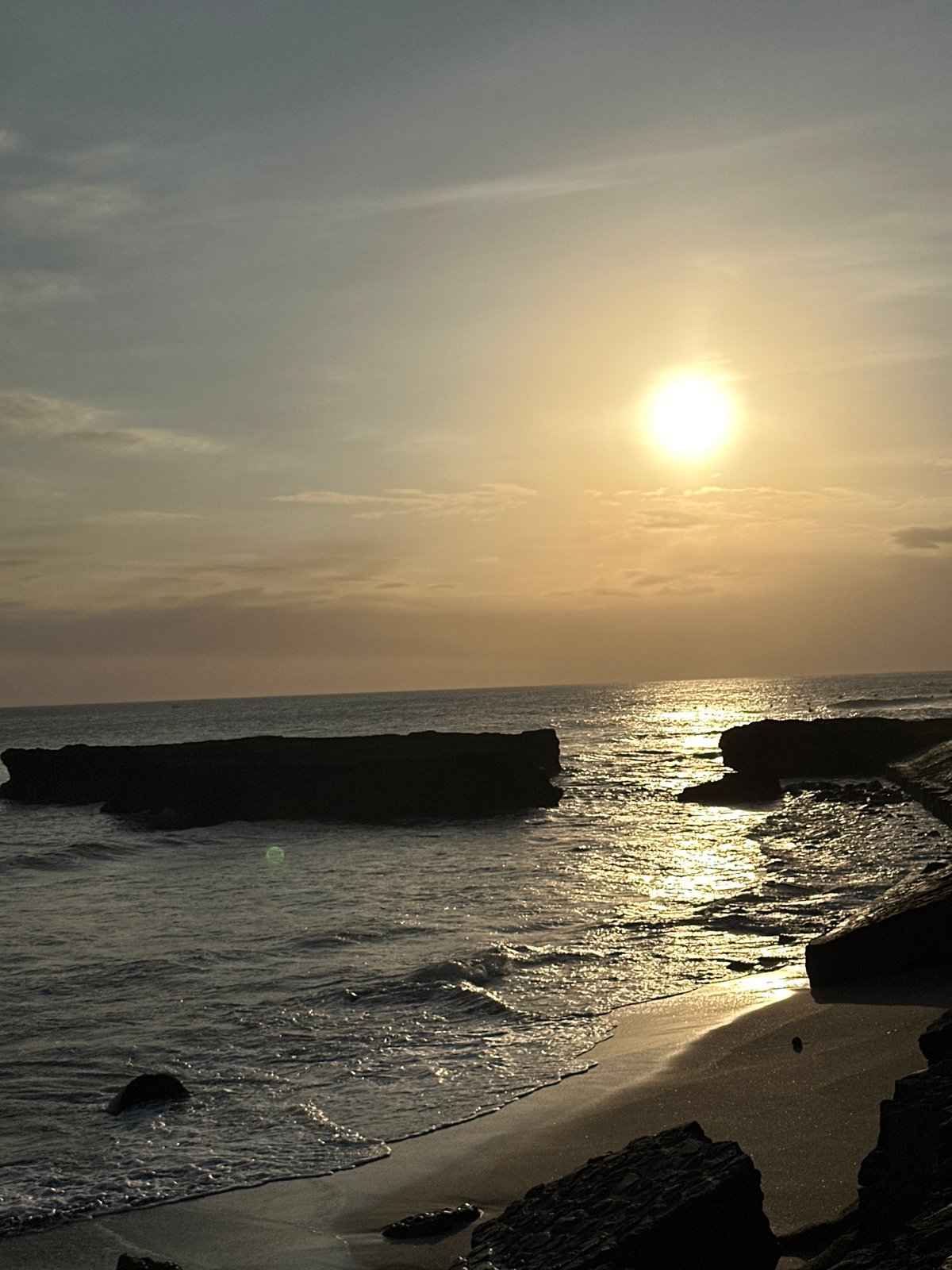 People gather on rocky outcrop during hazy morning in North Kuta