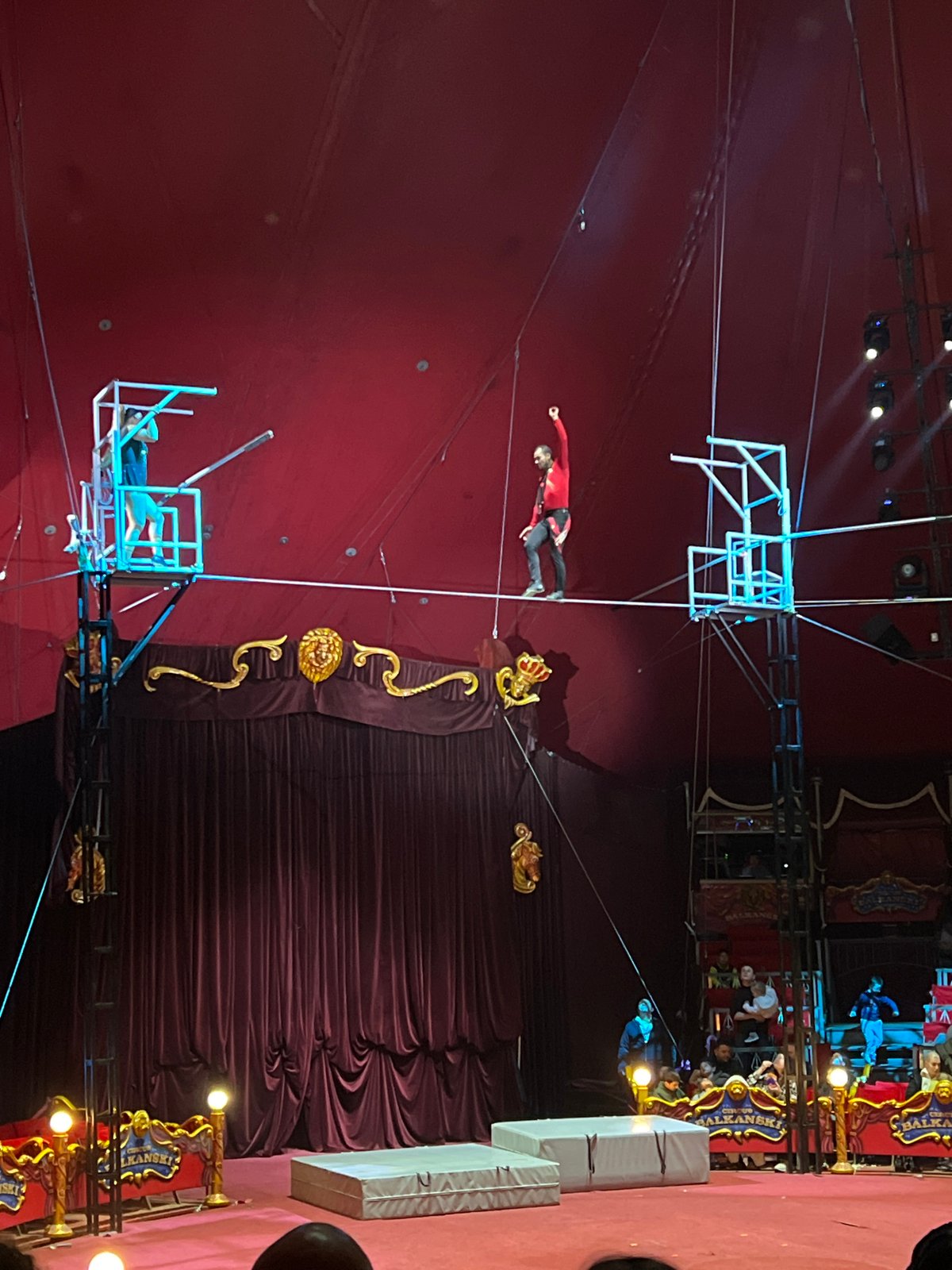 Circus acrobat performs tightrope act between elevated platforms