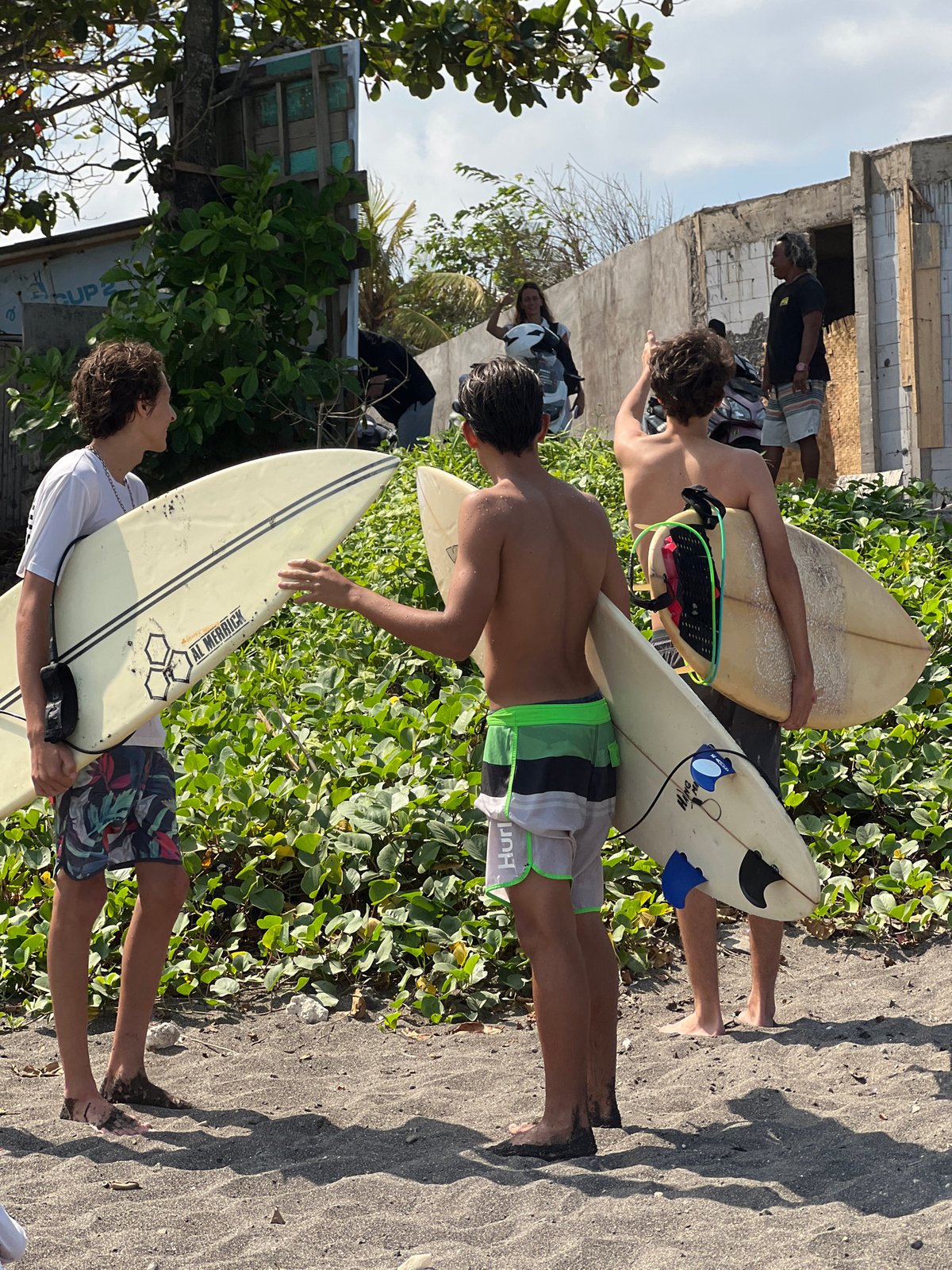 Surfers and beachgoers on Mengwi's volcanic sand coast