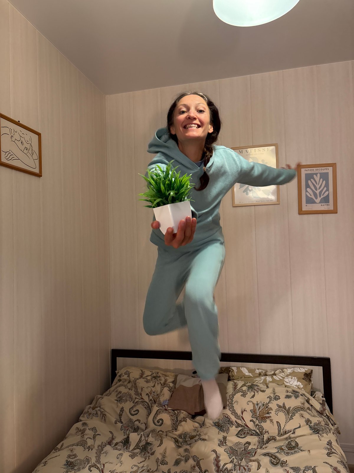Woman jumps joyfully indoors holding plant in Gelendzhik