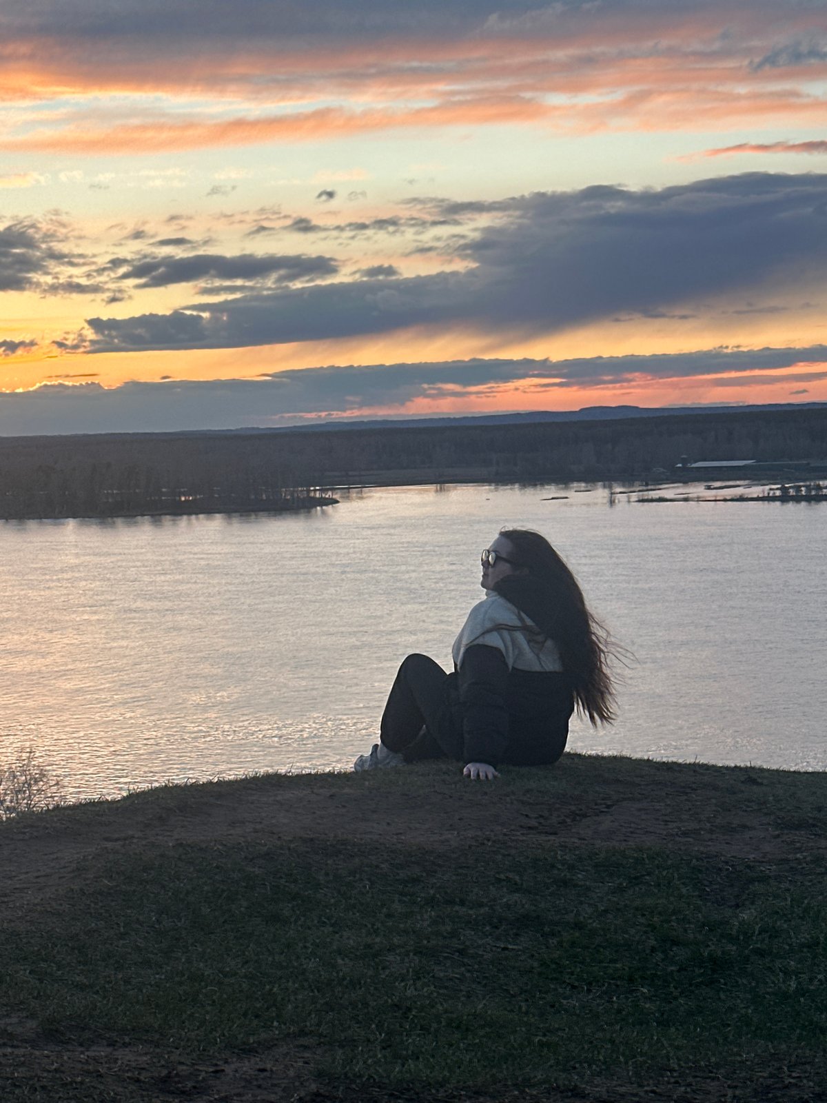 Person watches sunset over water in Ольховка, Russia