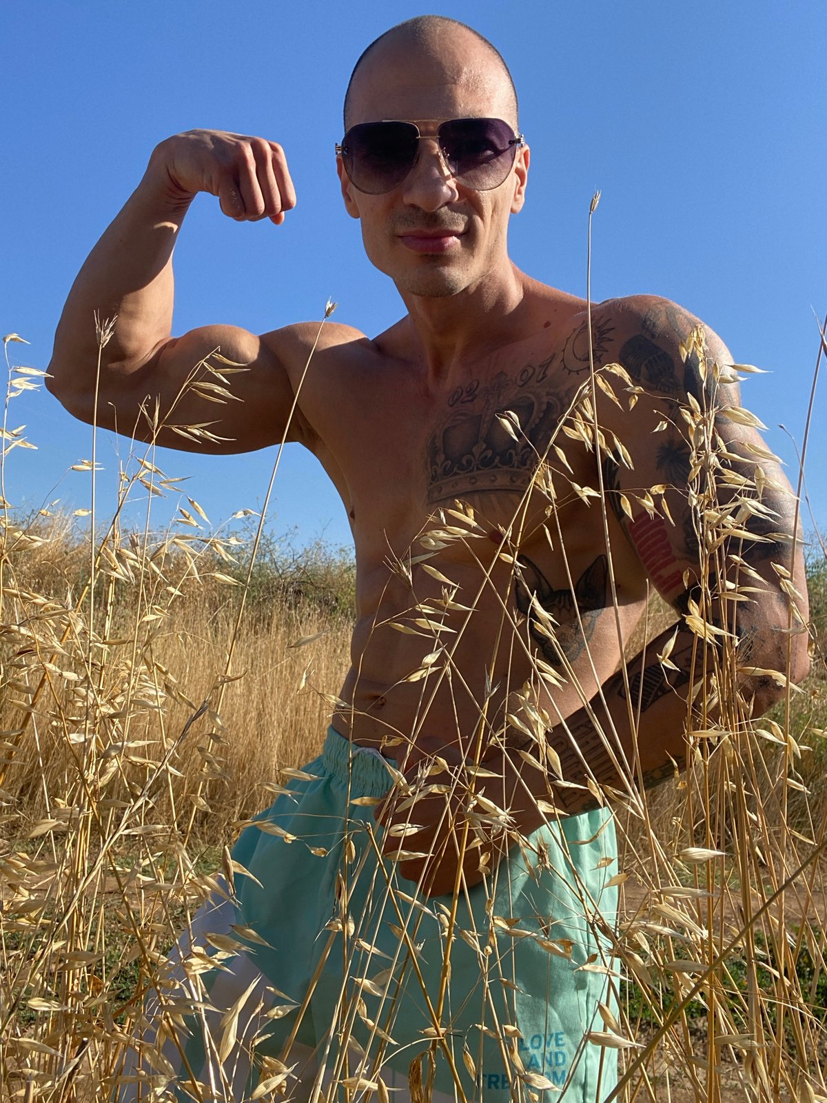 Tattooed figure poses and jumps in a dry Bulgarian field