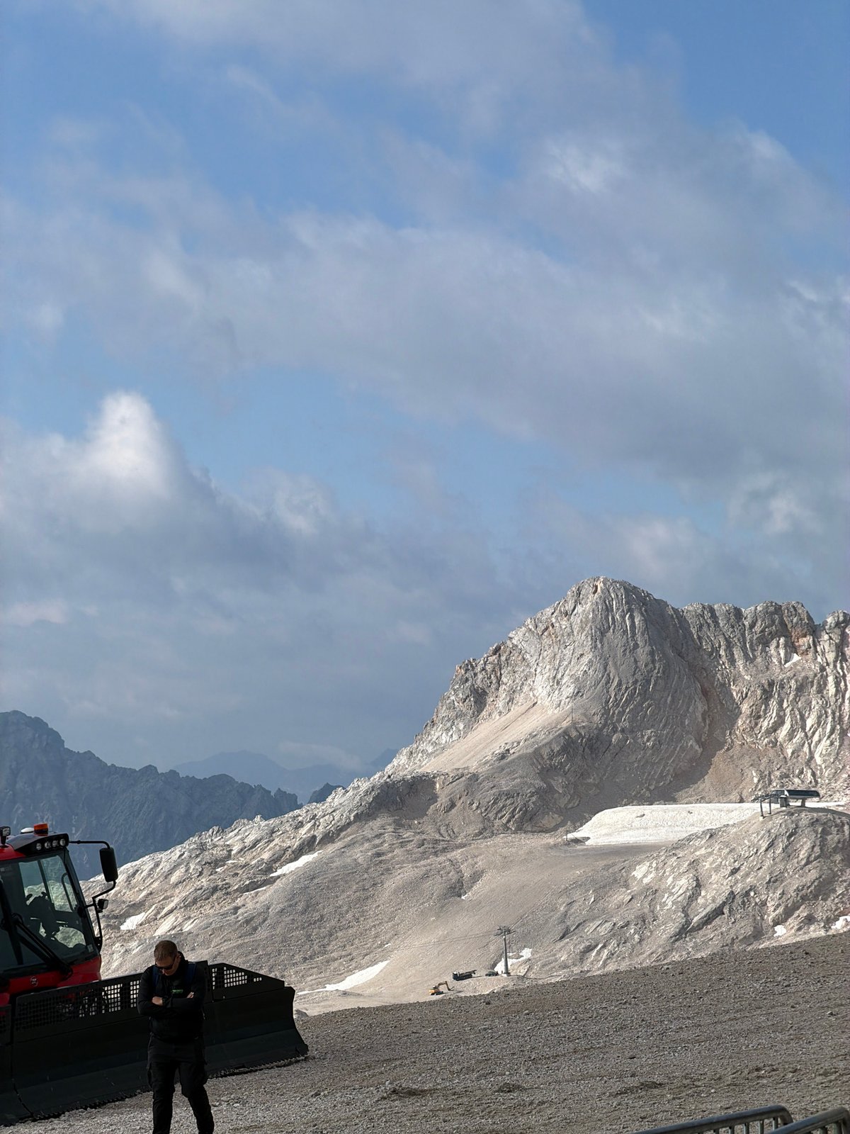 Red snow groomers parked on summer terrain in the Bavarian Alps
