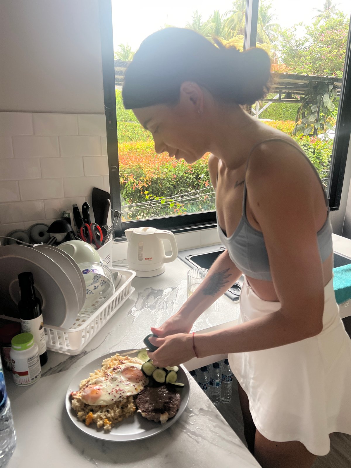 Woman cooks breakfast with fried eggs in Thai kitchen