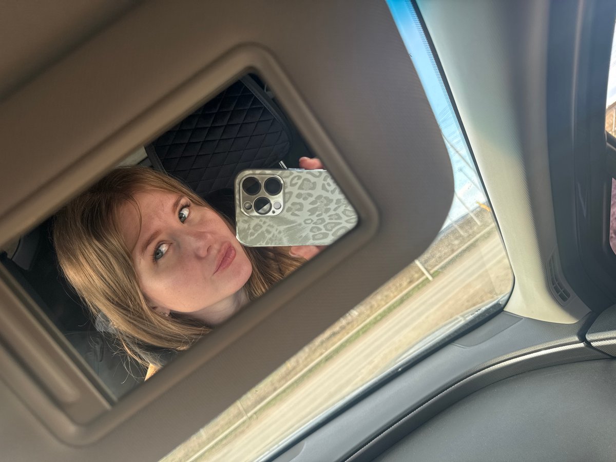 Woman takes selfie in car vanity mirror in Горный, Russia