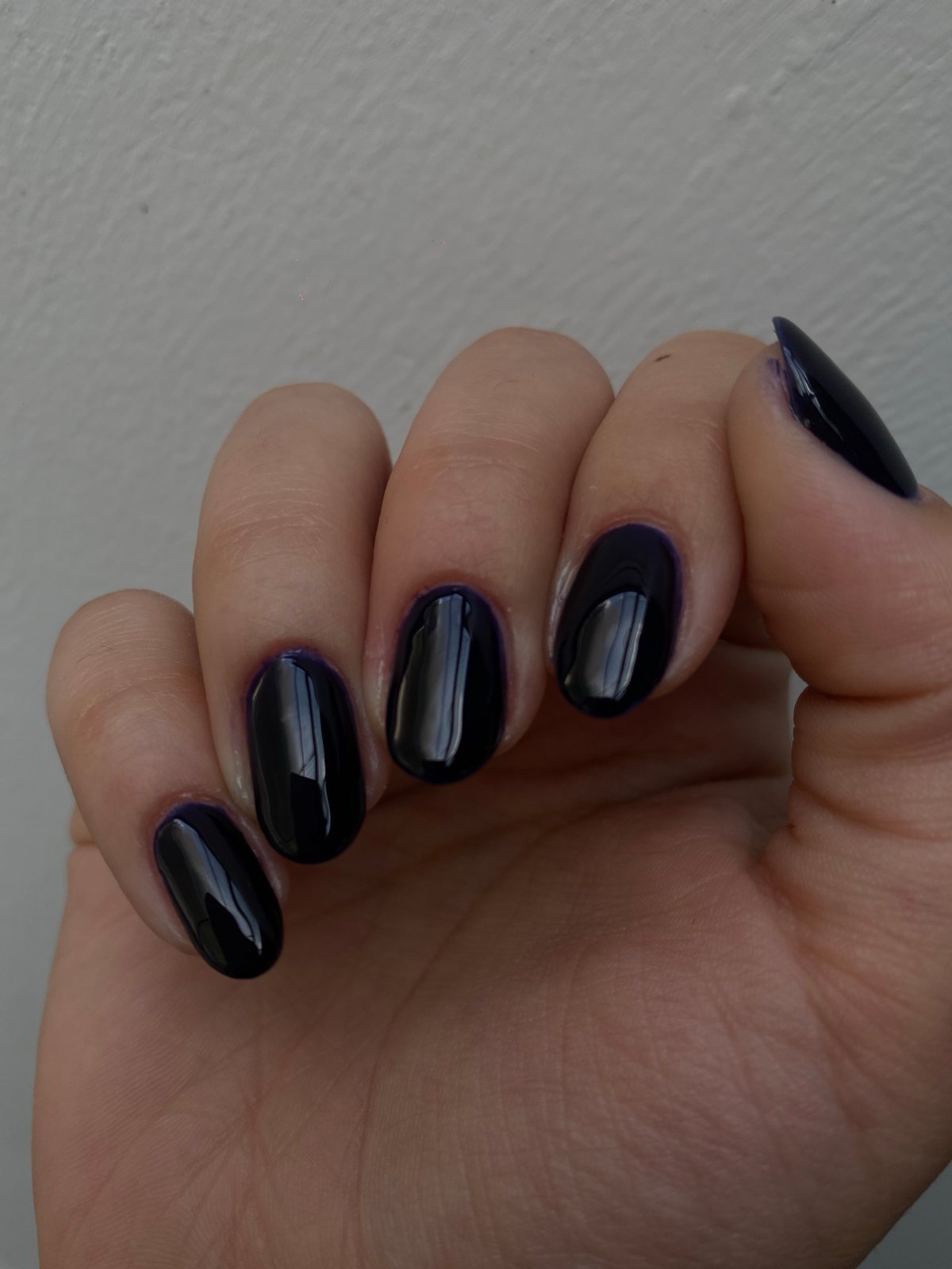 Woman's manicured hand with dark polish observed in close-up