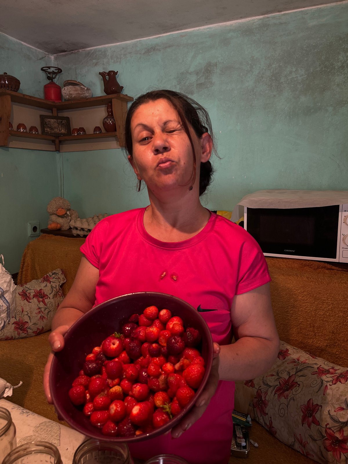 Woman prepares traditional strawberry compote in Bulgarian village kitchen