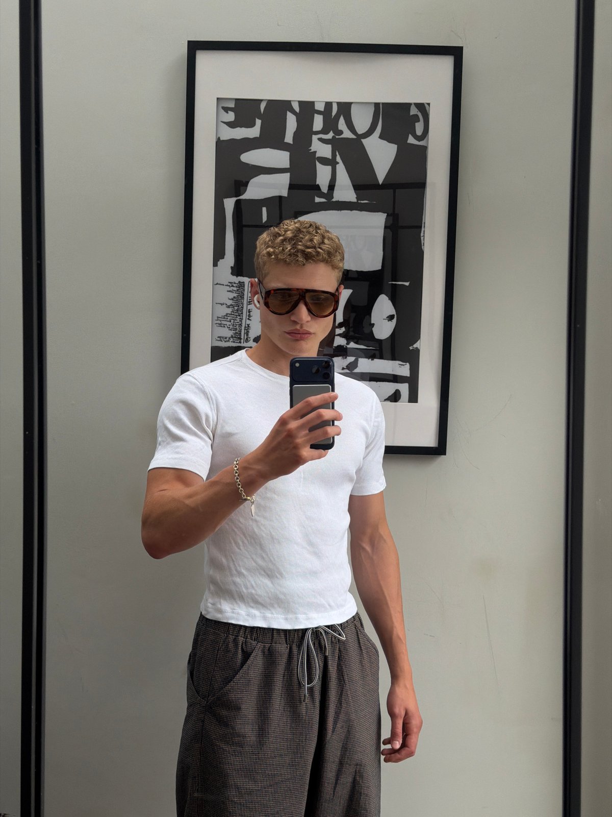 Mirror selfie in a London home, checkered trousers and white tee