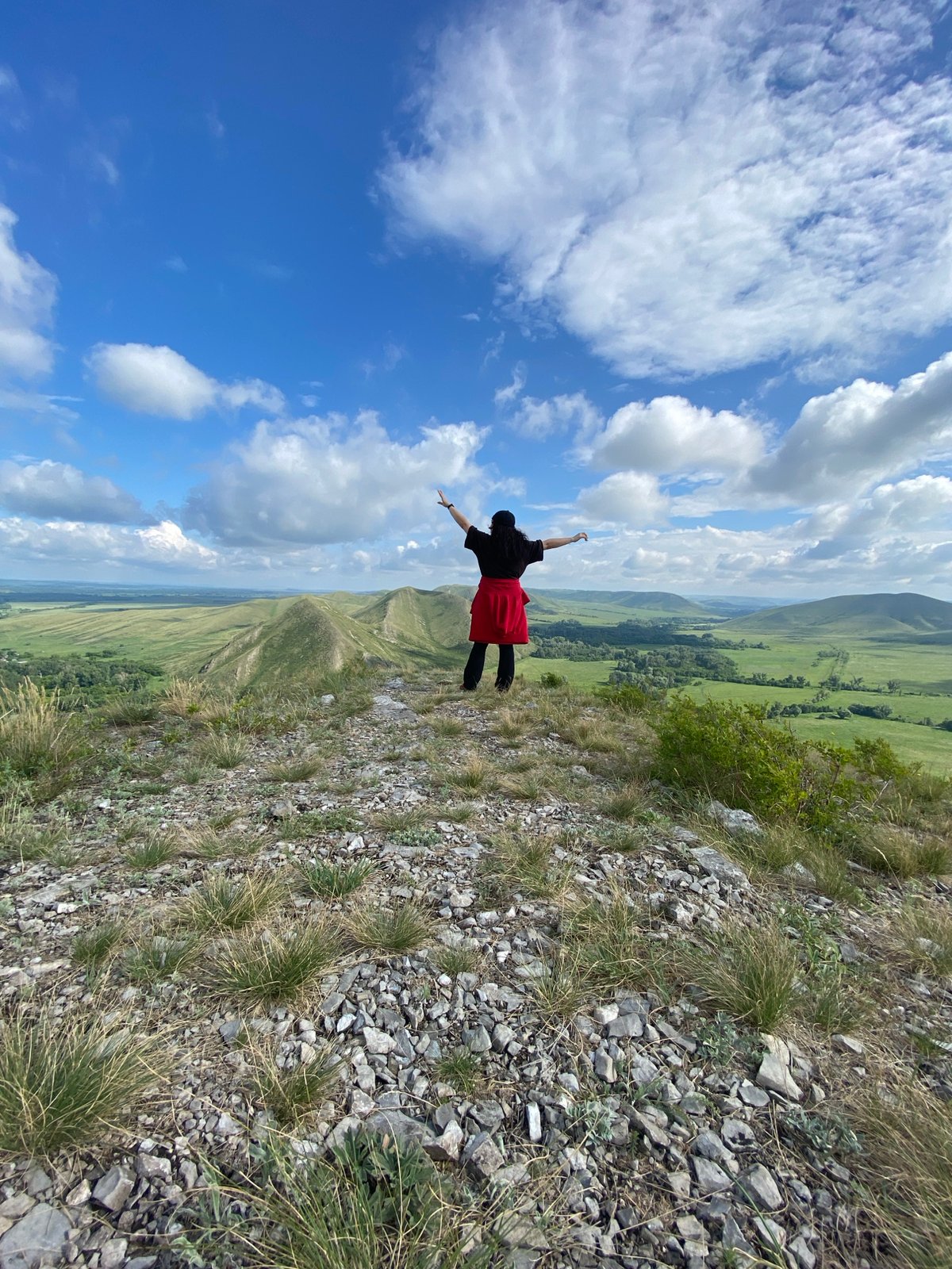 Person poses on Russian hilltop overlooking valley at dawn