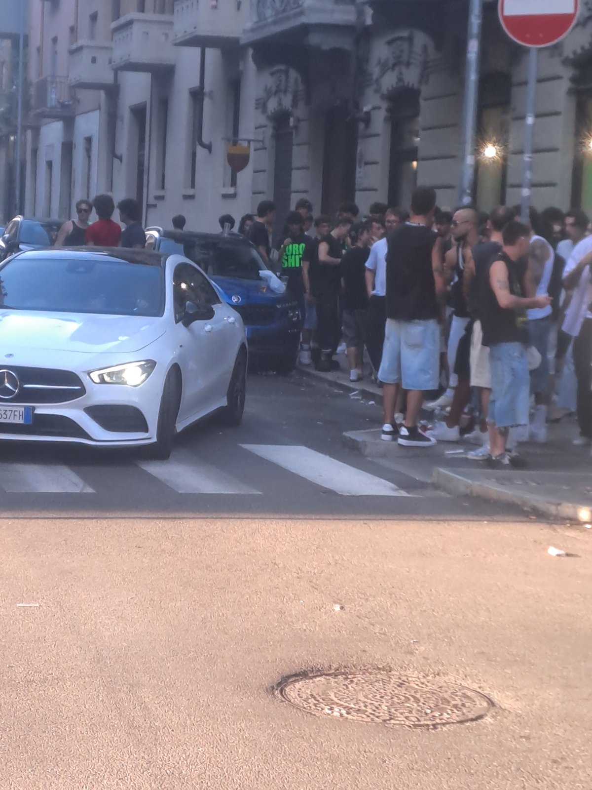 White Mercedes parked on crosswalk amid Turin street crowd