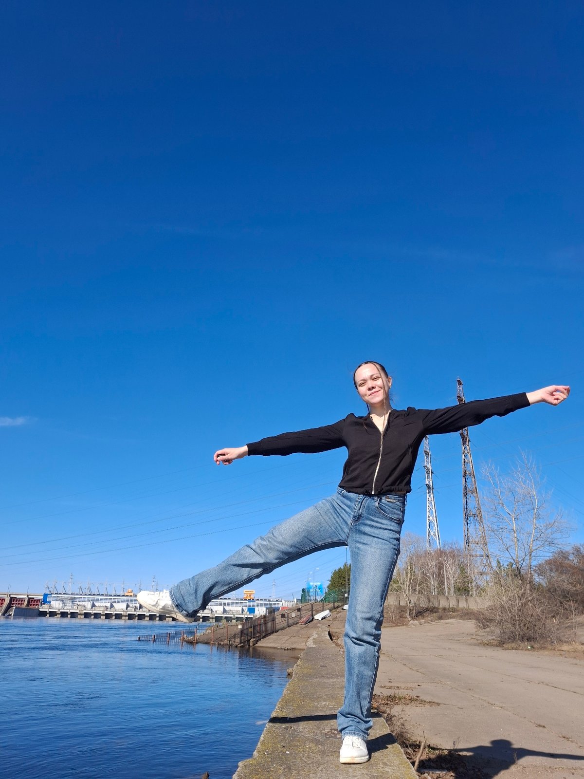 Woman photographs herself along Chaikovsky waterfront during sunny morning