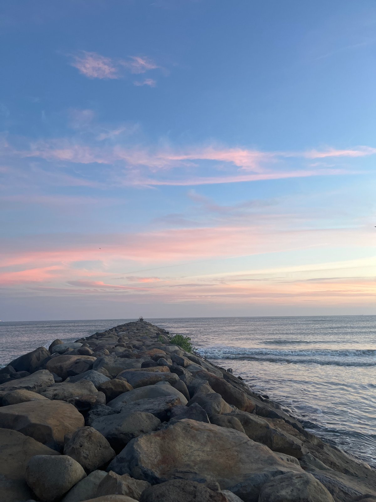 Sunset over a quiet Indonesian coastal jetty and shoreline