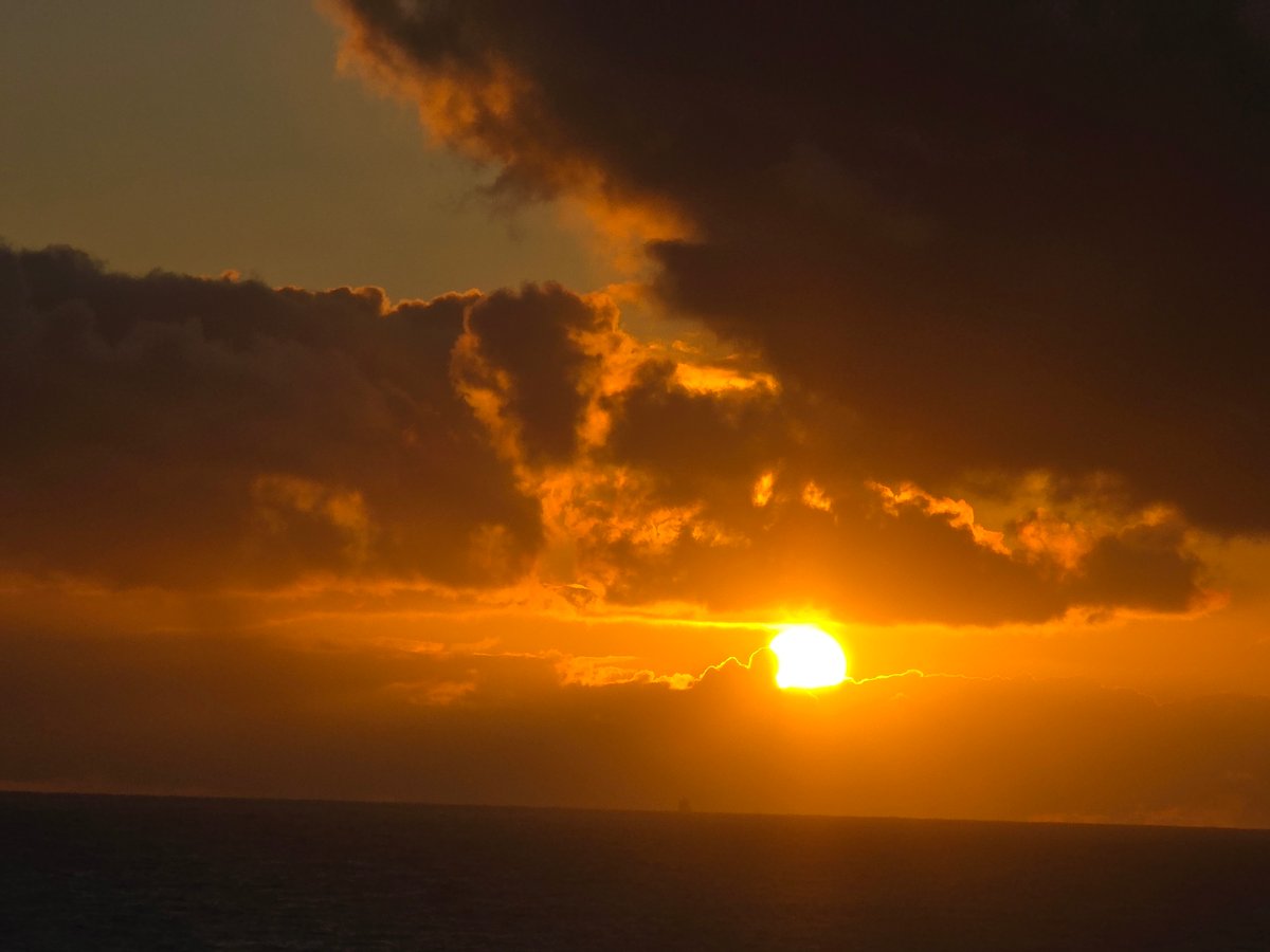 Orange sunset pierces dark clouds over Norwegian coastline