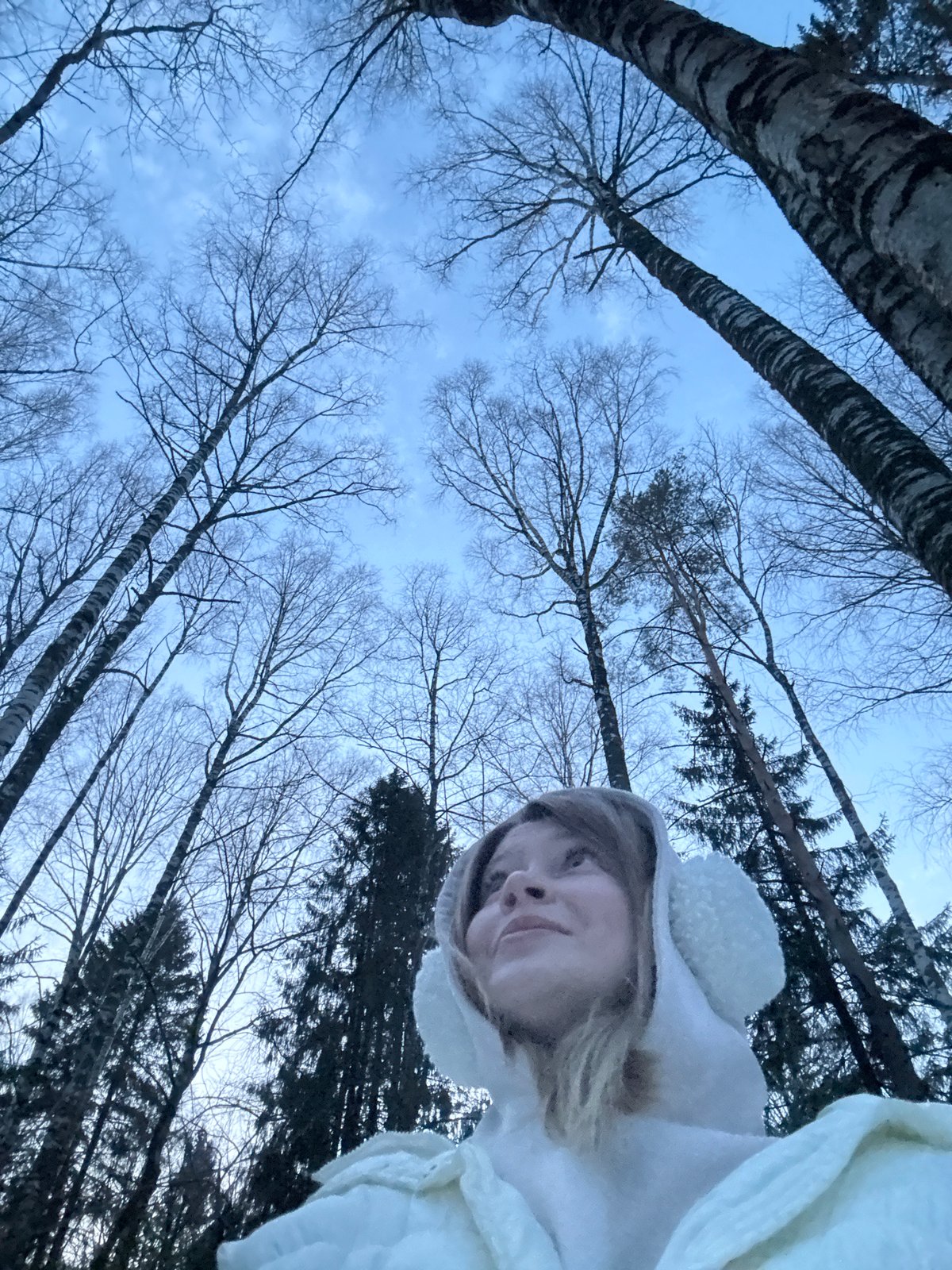 Woman explores snowy forest near Vassyata, Russia winter afternoon