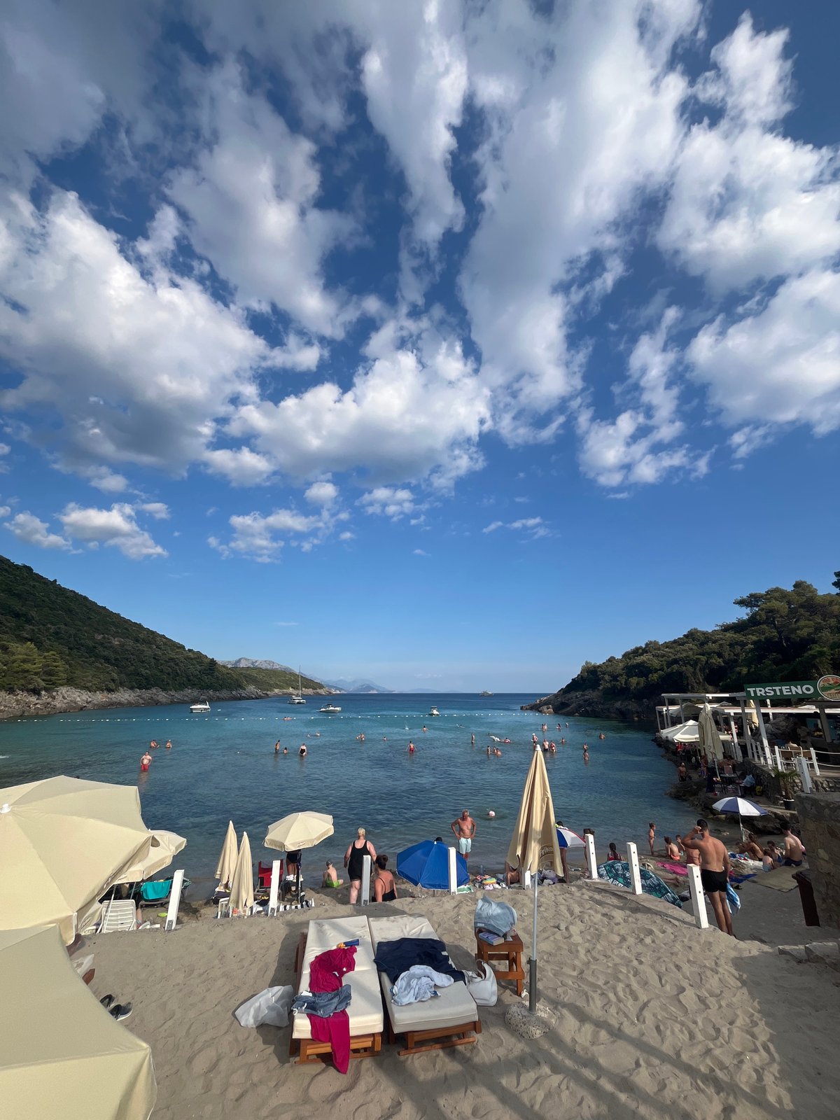 Swimmers and boats fill a sunny Montenegrin Adriatic beach