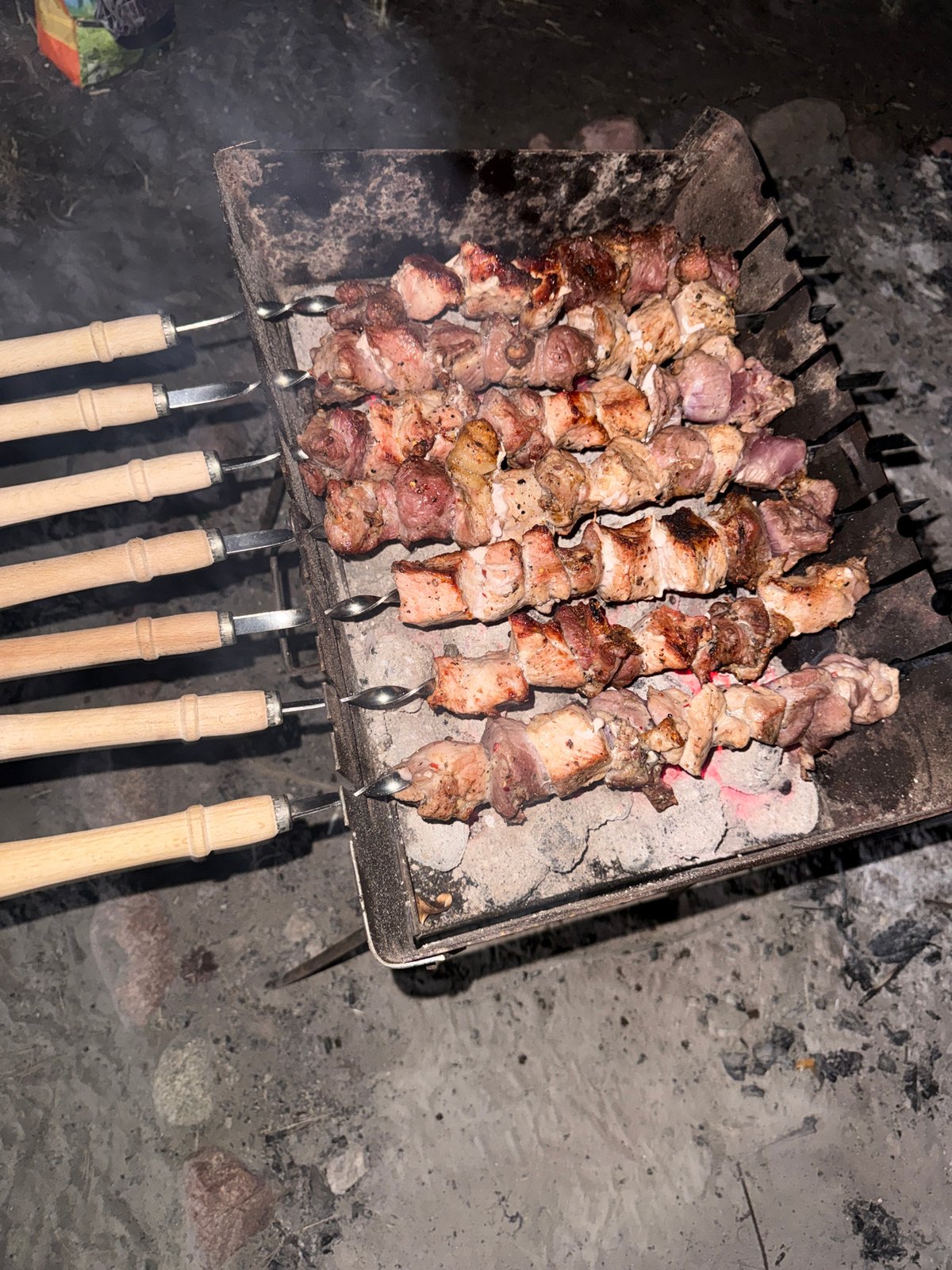 Meat skewers grilling over hot coals in rural Poland