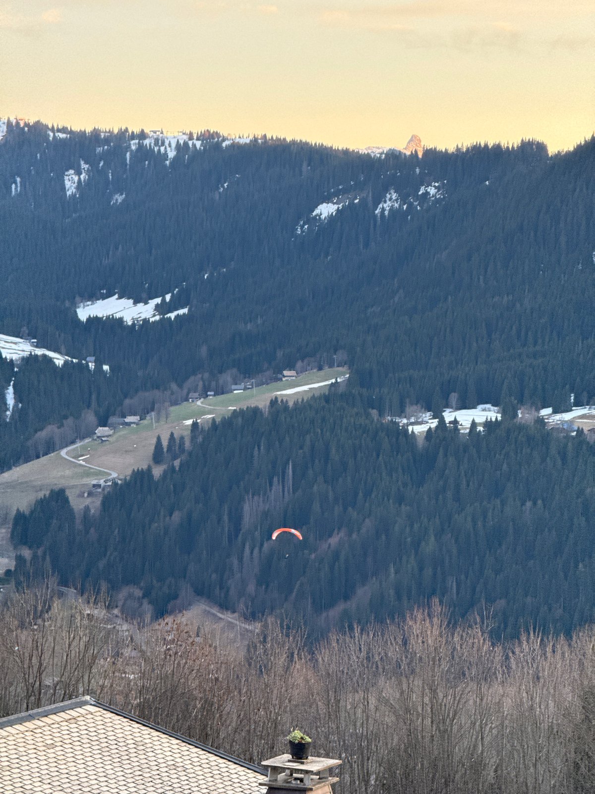 Red paraglider spotted over snowy Morzine forests Monday afternoon