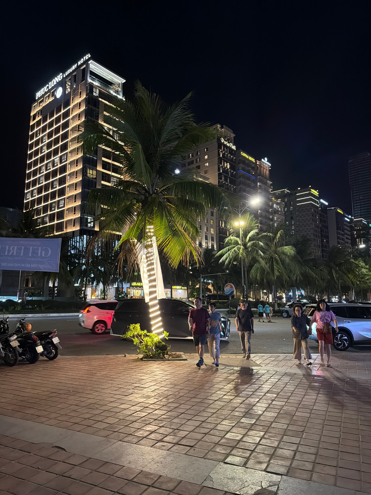 Nighttime walkway scene in Da Nang with kiosk and hotels