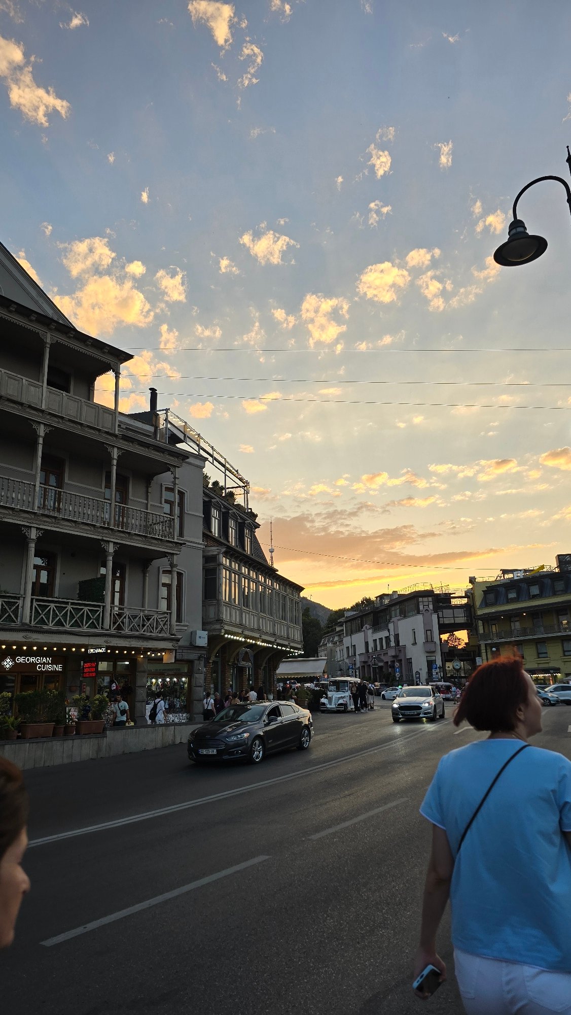 Tbilisi street at dusk: juice stand, restaurant sign, fading sky