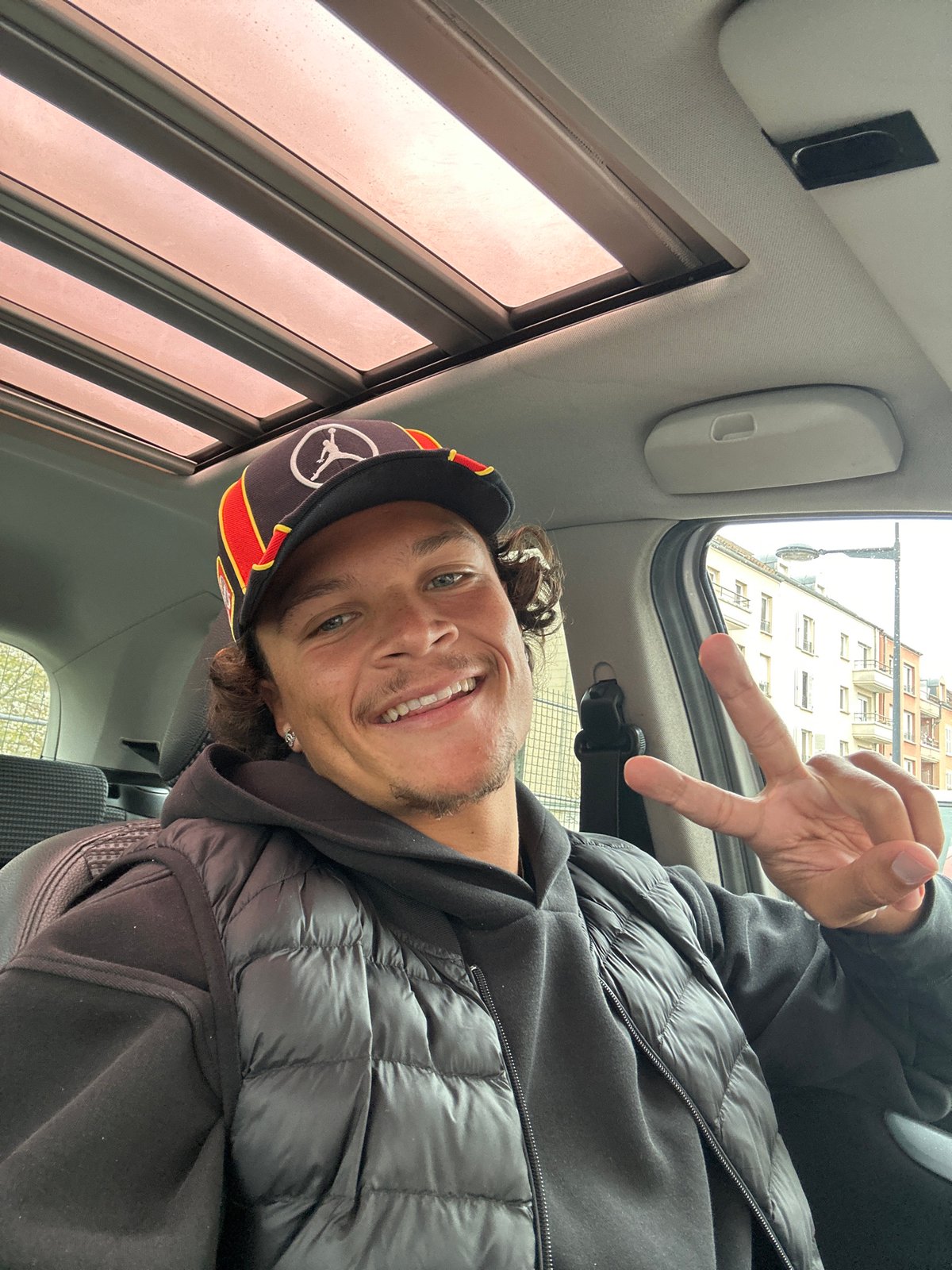 Man takes selfie in car wearing hoodie and cap