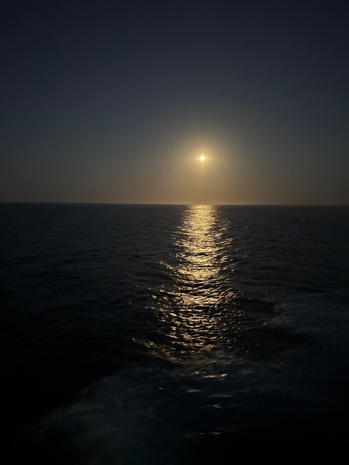 Sun and moon over the Atlantic, light paths on dark water