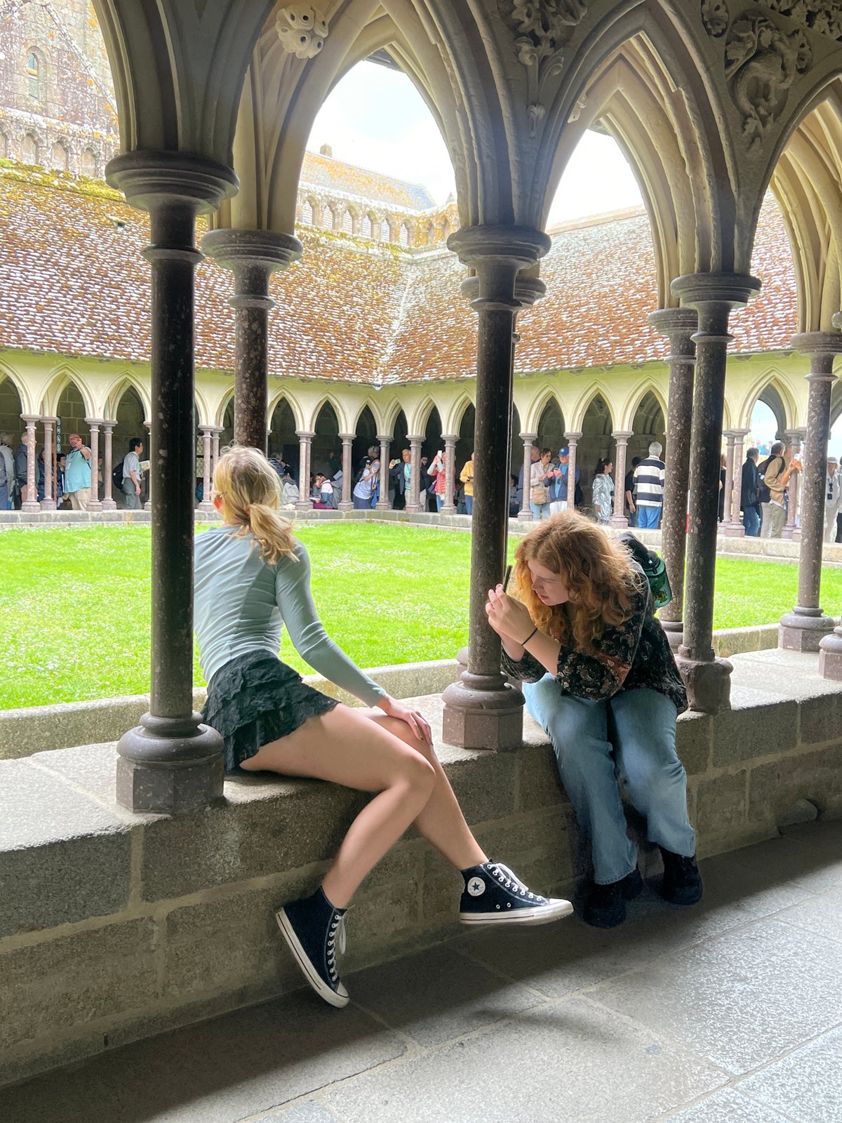 Two women rest in Mont-Saint-Michel cloister courtyard