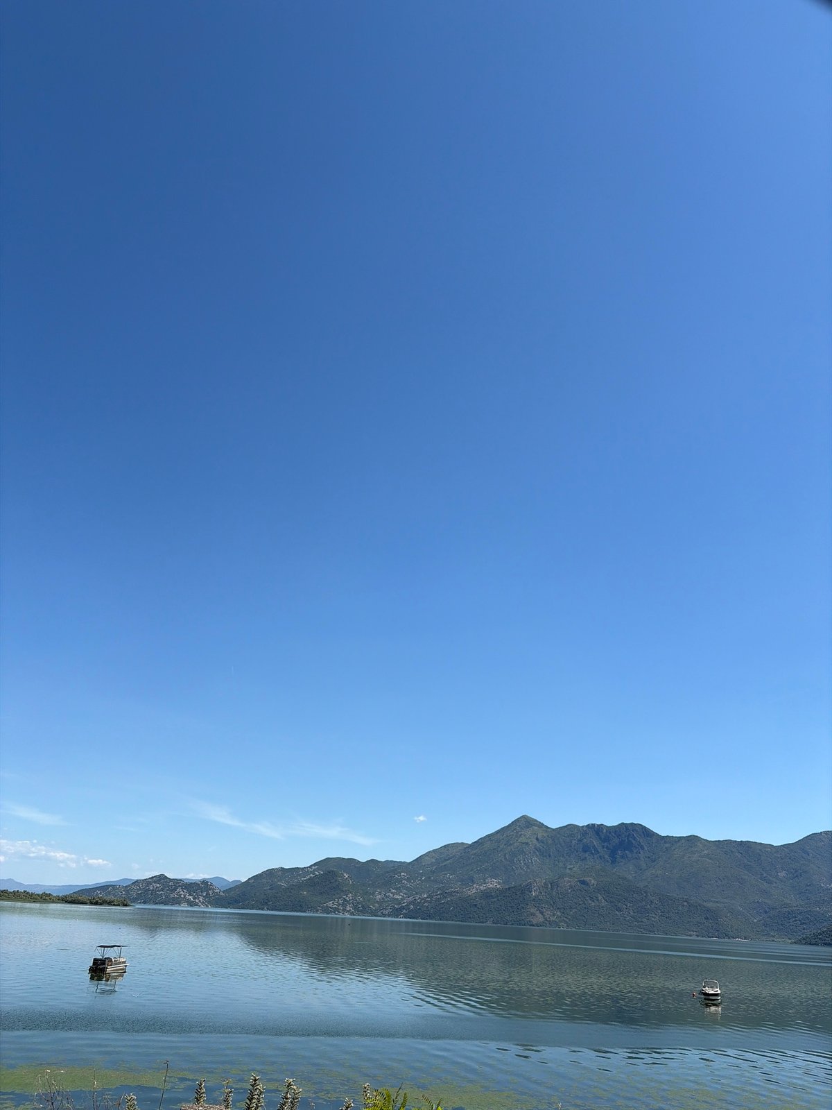 Still lake, mountain reflections, two boats near Podgorica